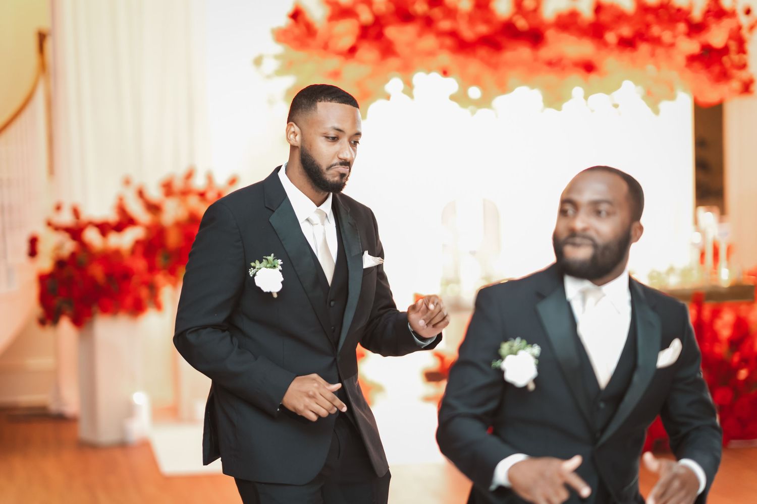 Groomsmen in formal black and white attire celebrating at wedding reception.