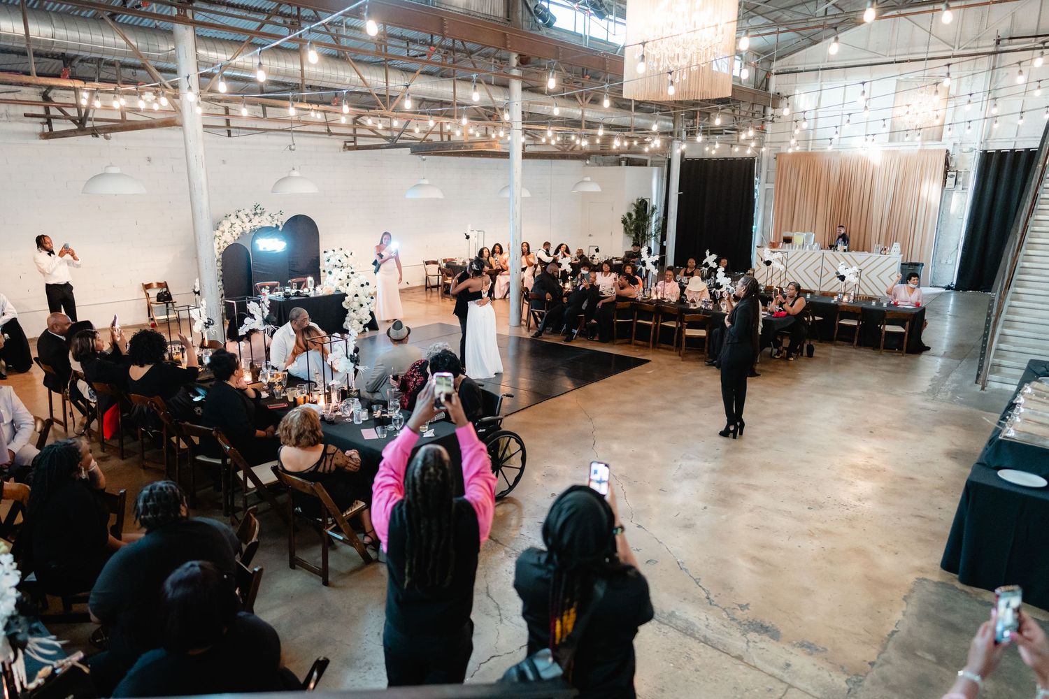 Panoramic shot of industrial wedding venue with exposed ceiling and guest tables.