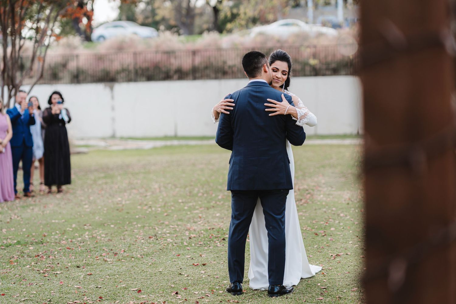 Wedding couple embracing outdoors in a park setting during their special day.