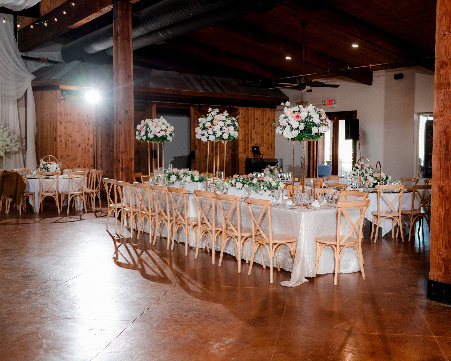 Rustic wedding reception venue with wooden floors and elegant table settings.