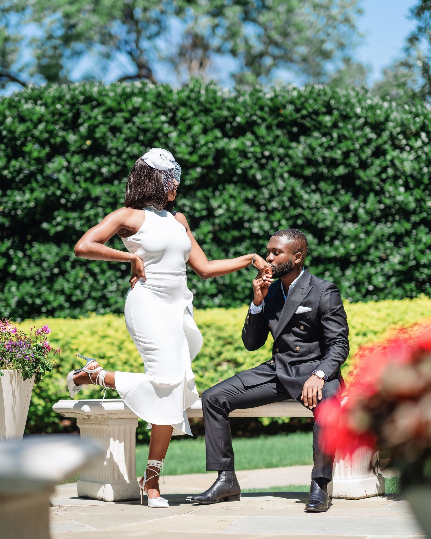 A romantic photoshoot in a garden featuring elegant formal wear and stone benches.