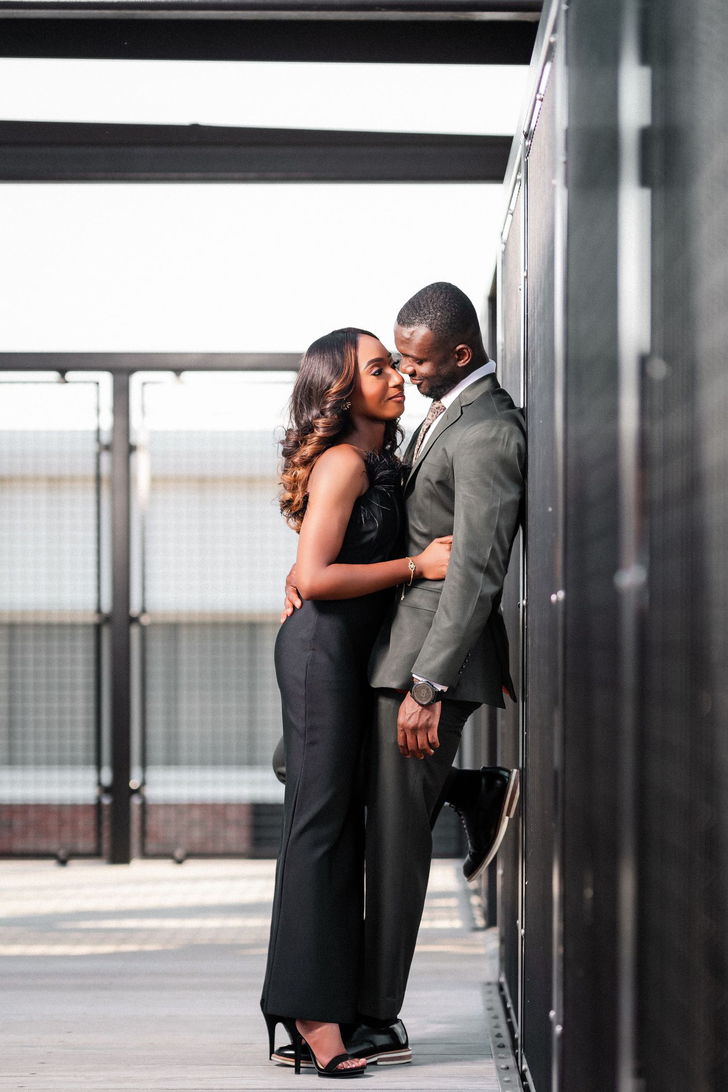 Couple sharing tender moments against modern architectural elements in black formal attire.