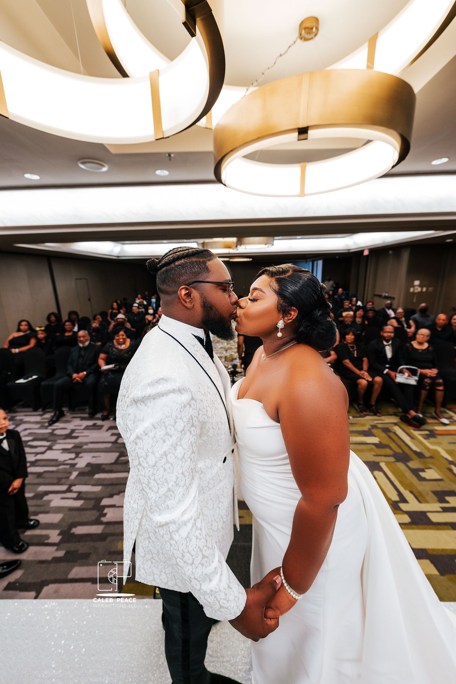 Wedding first dance sequence in an elegant ballroom with guests watching in the background.