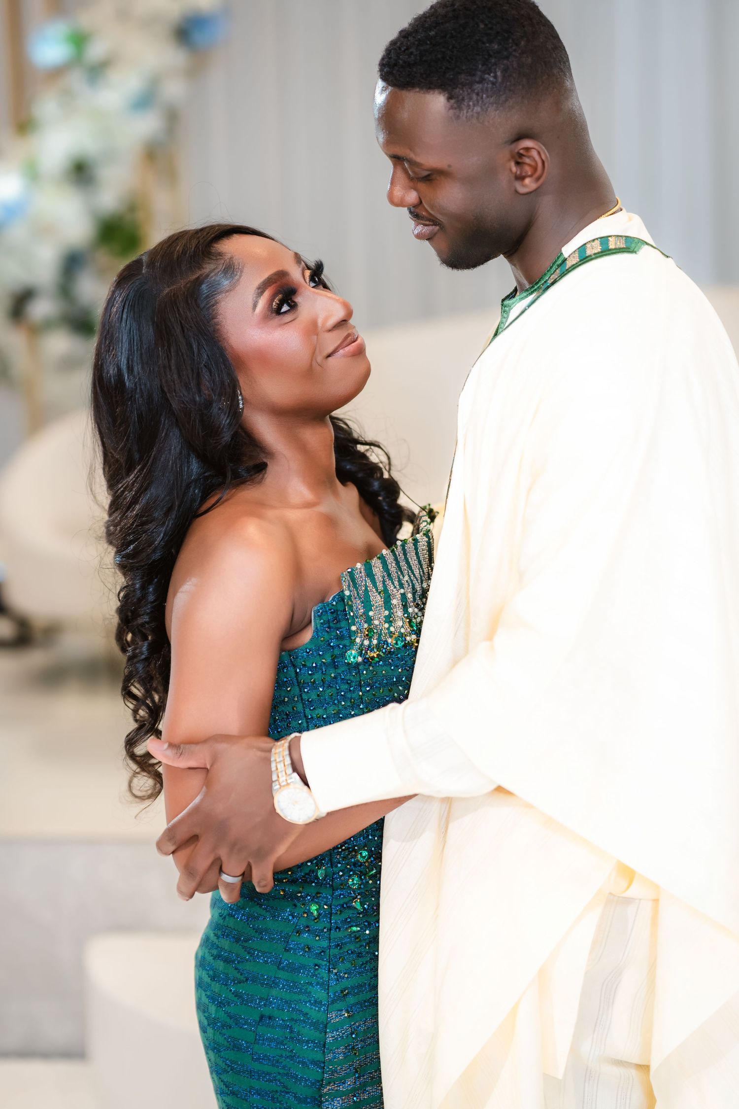 A couple in formal attire share intimate moments during a wedding photoshoot with emerald green accents.