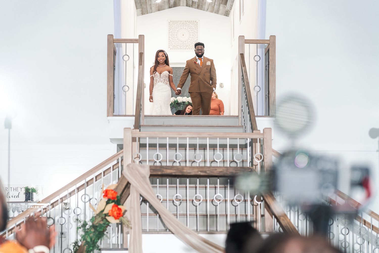 Wedding party members pose on a white balcony with decorative railings.