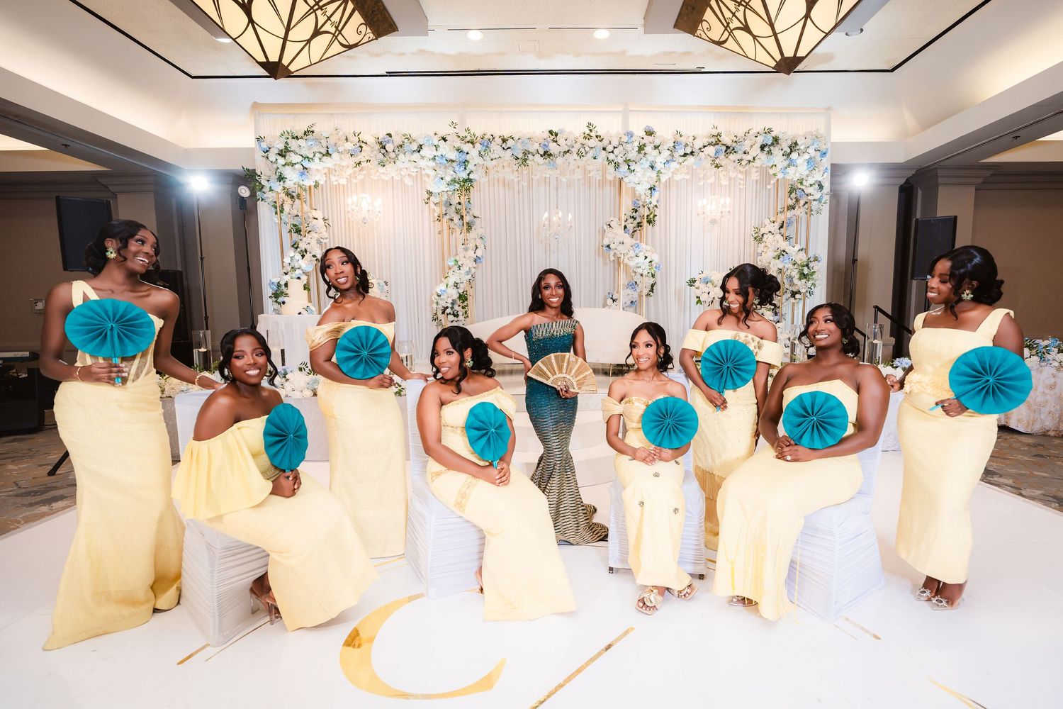 Wedding party lineup in front of floral backdrop with turquoise and white color scheme.
