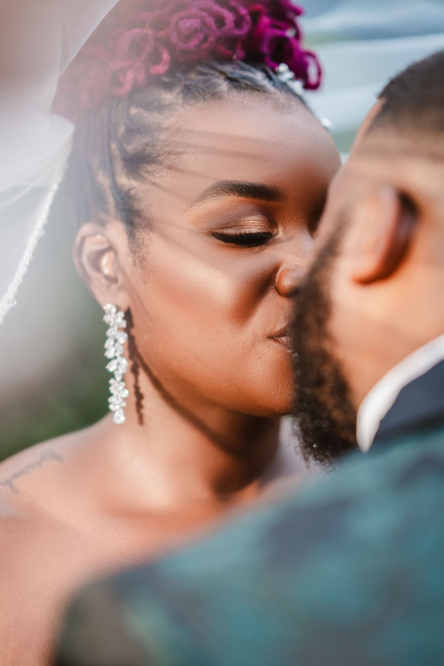 Close-up romantic wedding portrait showing tender moment between newlyweds with soft focus and pink floral details.