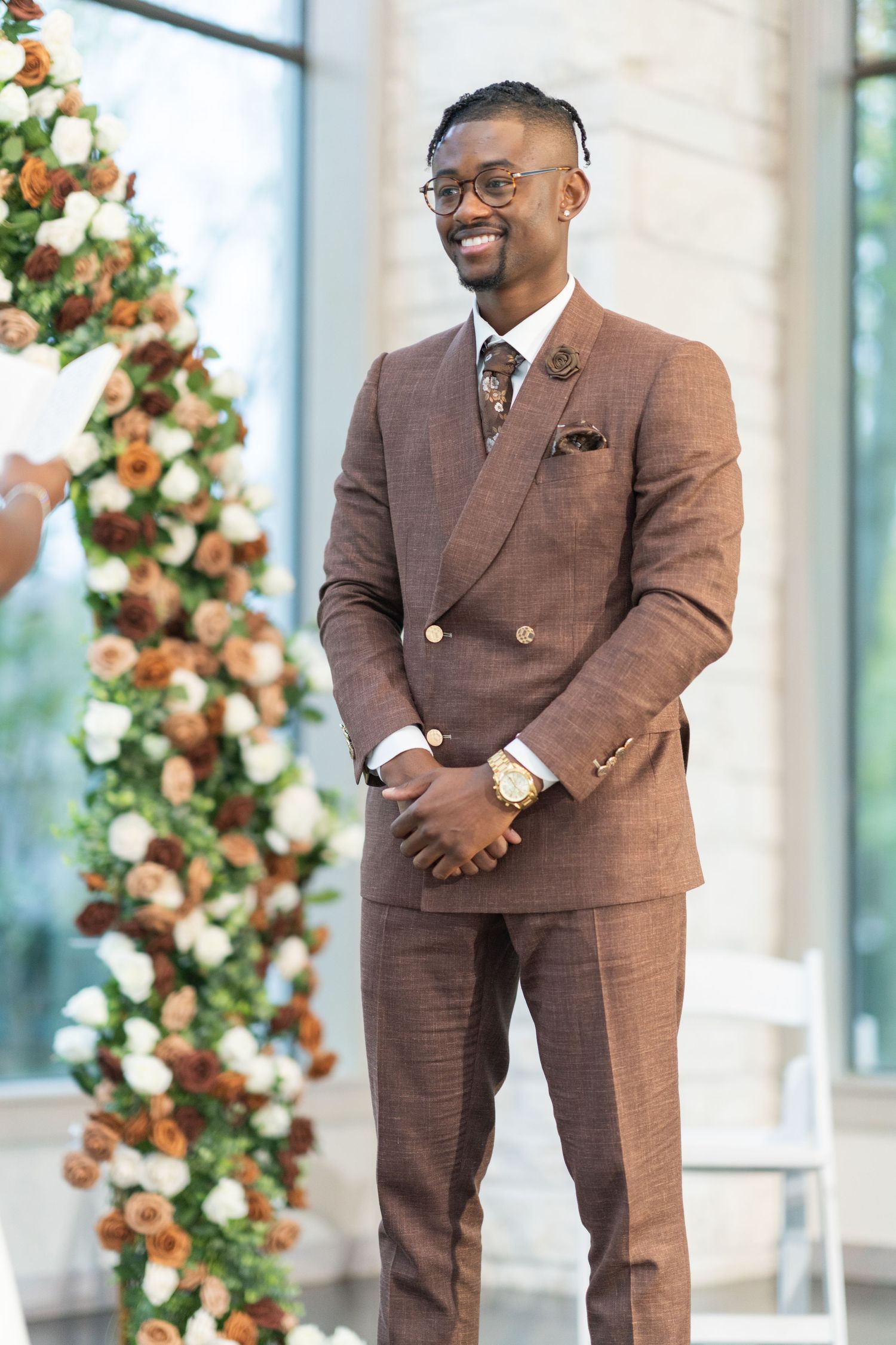 A series of photos showing a person in a tailored brown suit posing near floral decorations at an event.
