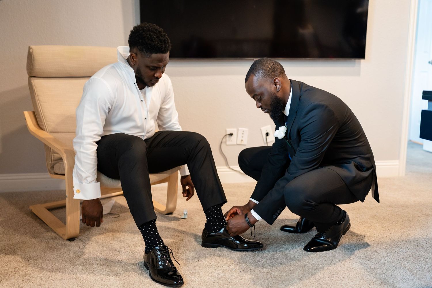 Two people kneeling on the floor during what appears to be a wedding preparation moment.