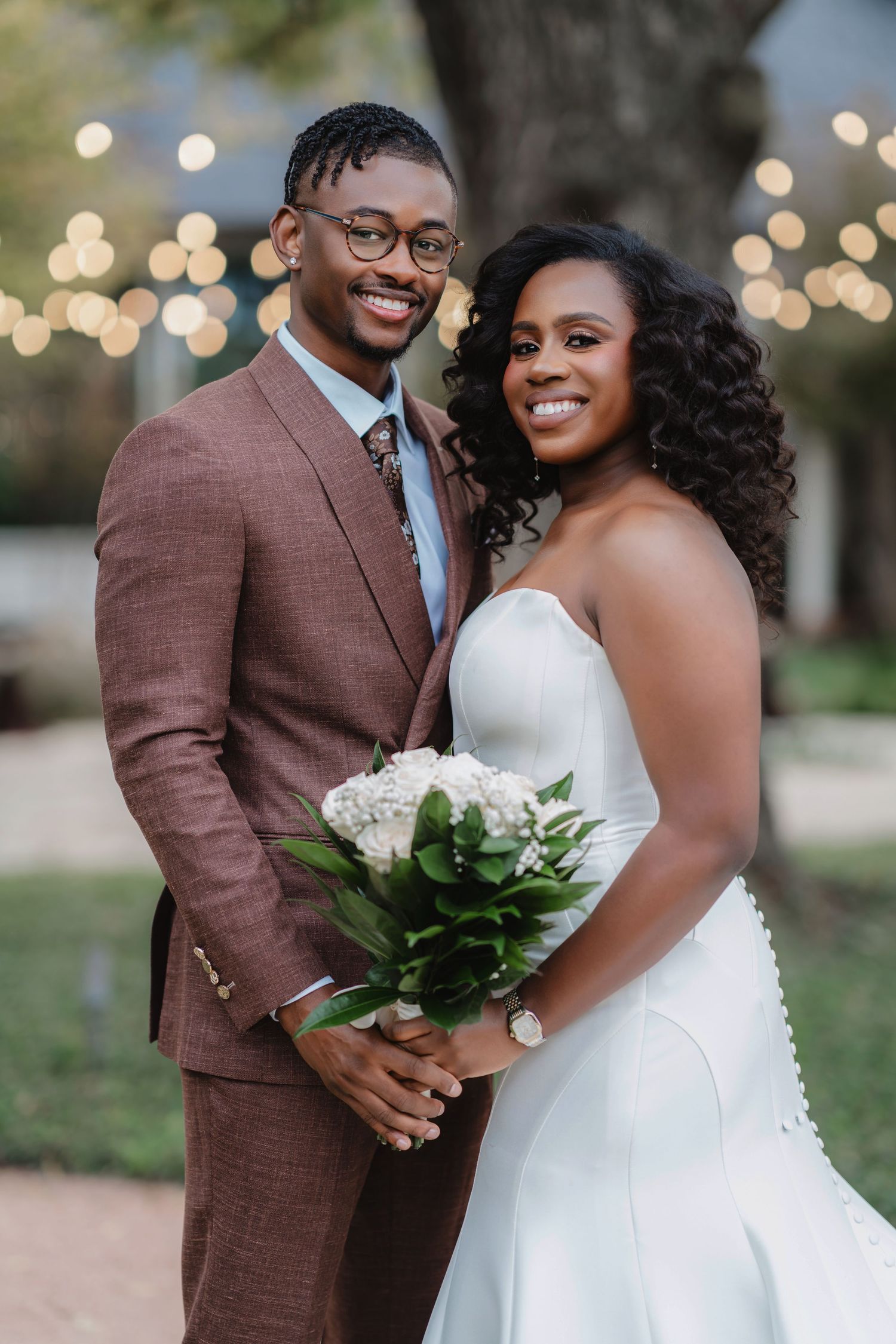 A romantic wedding couple poses outdoors with string lights and greenery in a series of intimate portraits.
