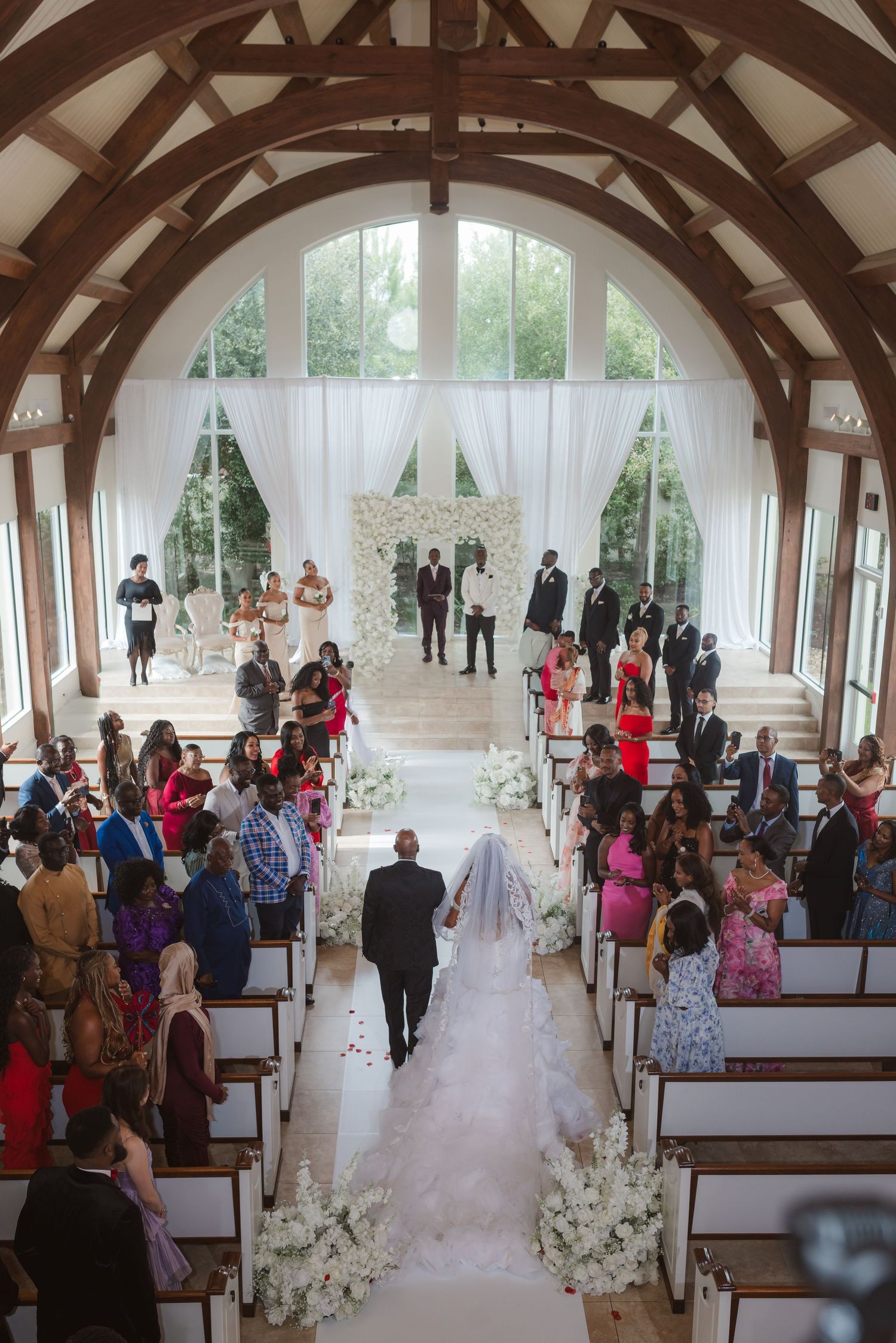 Elegant chapel interior with wooden beam arches and white decor during a wedding ceremony.