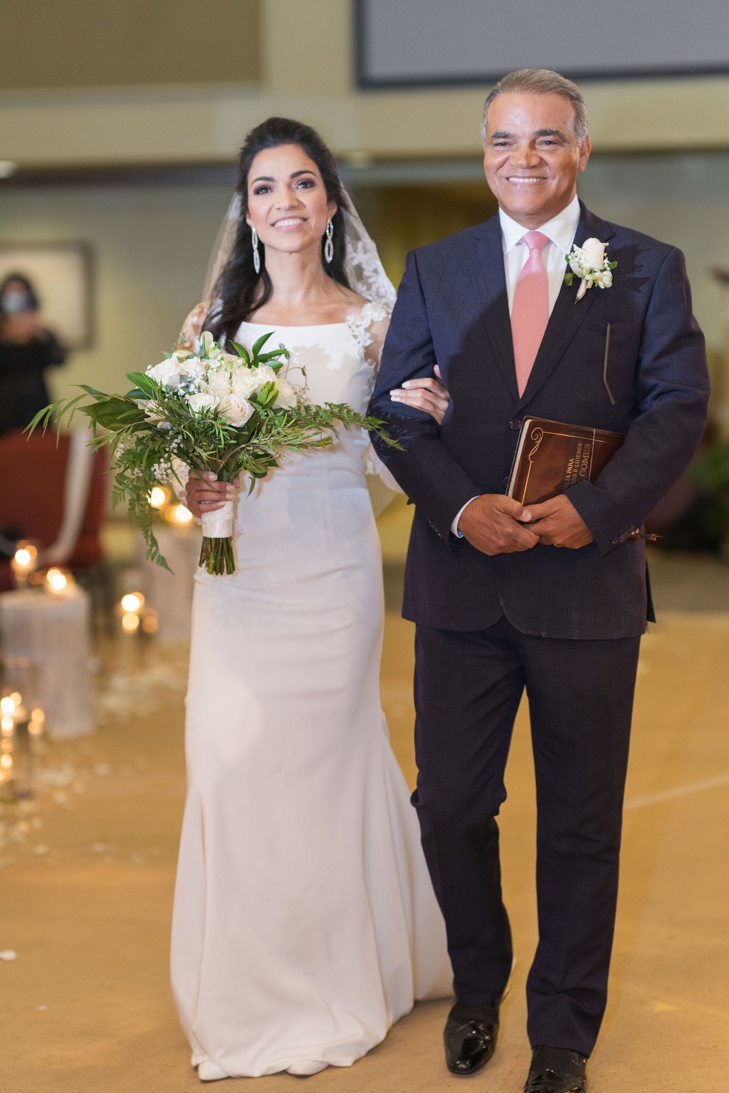 Wedding ceremony procession in a grand hall with elegant lighting and decor.