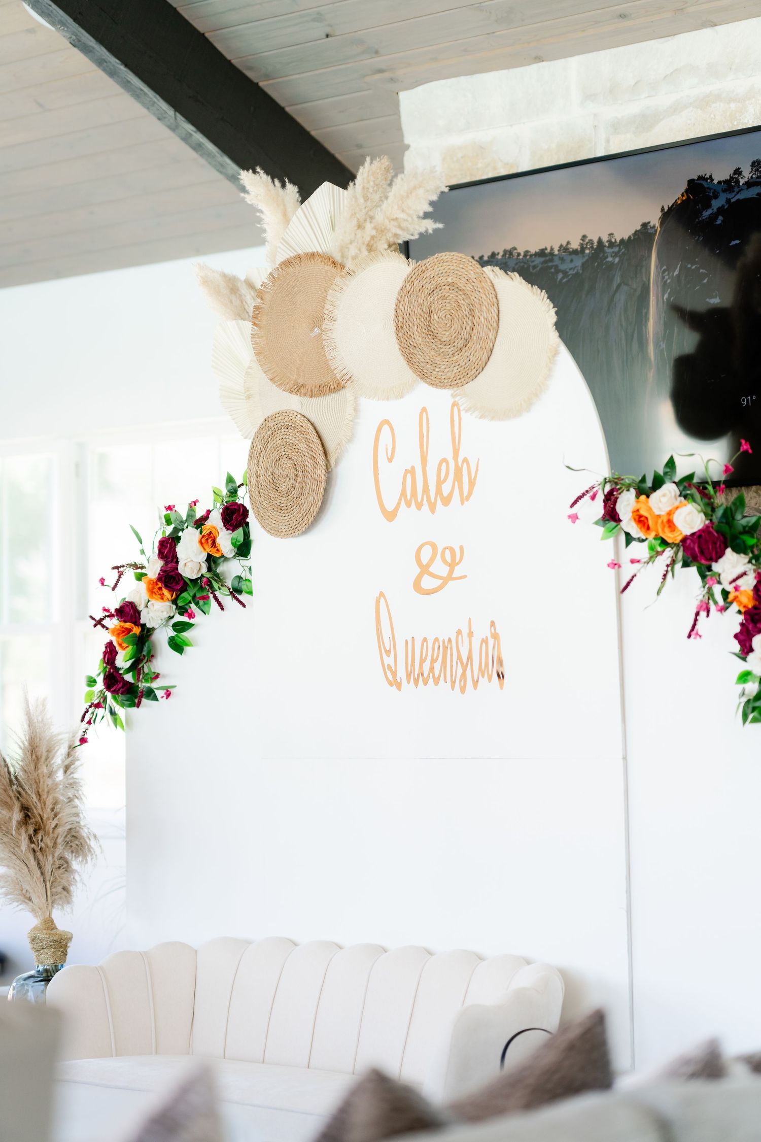 Elegant wedding decor featuring circular woven elements and floral arrangements against a white backdrop.