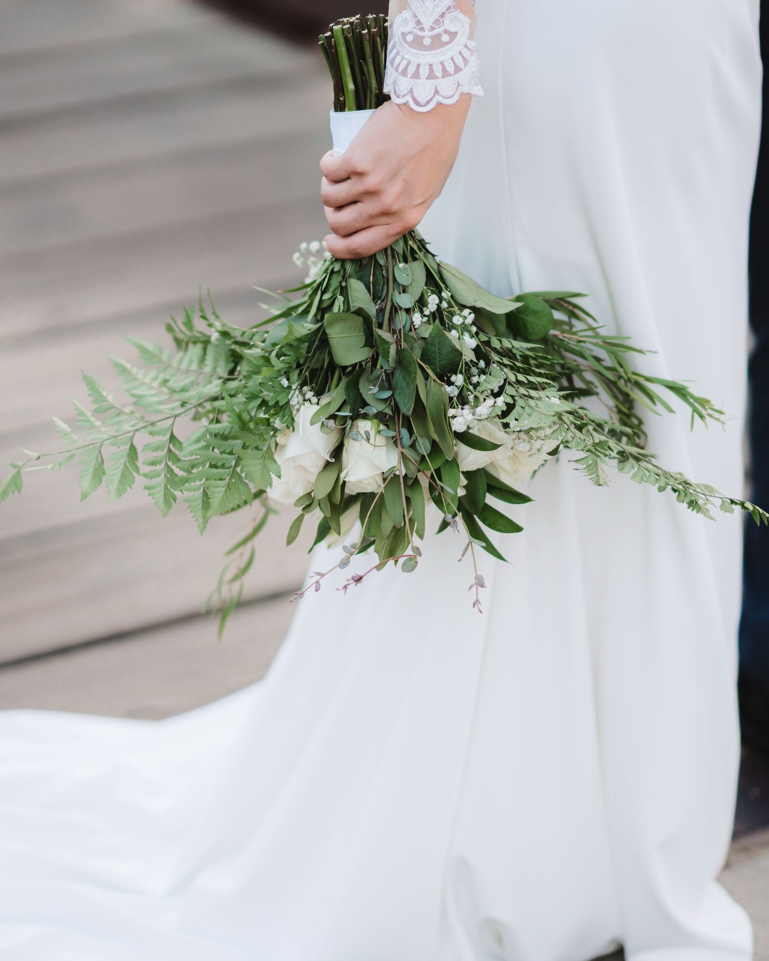 Close-up details of a bridal bouquet featuring white flowers and cascading green ferns.