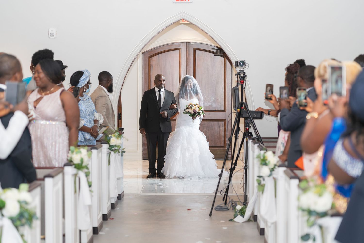Wedding ceremony venue with white chairs and floral decorations in elegant indoor setting.