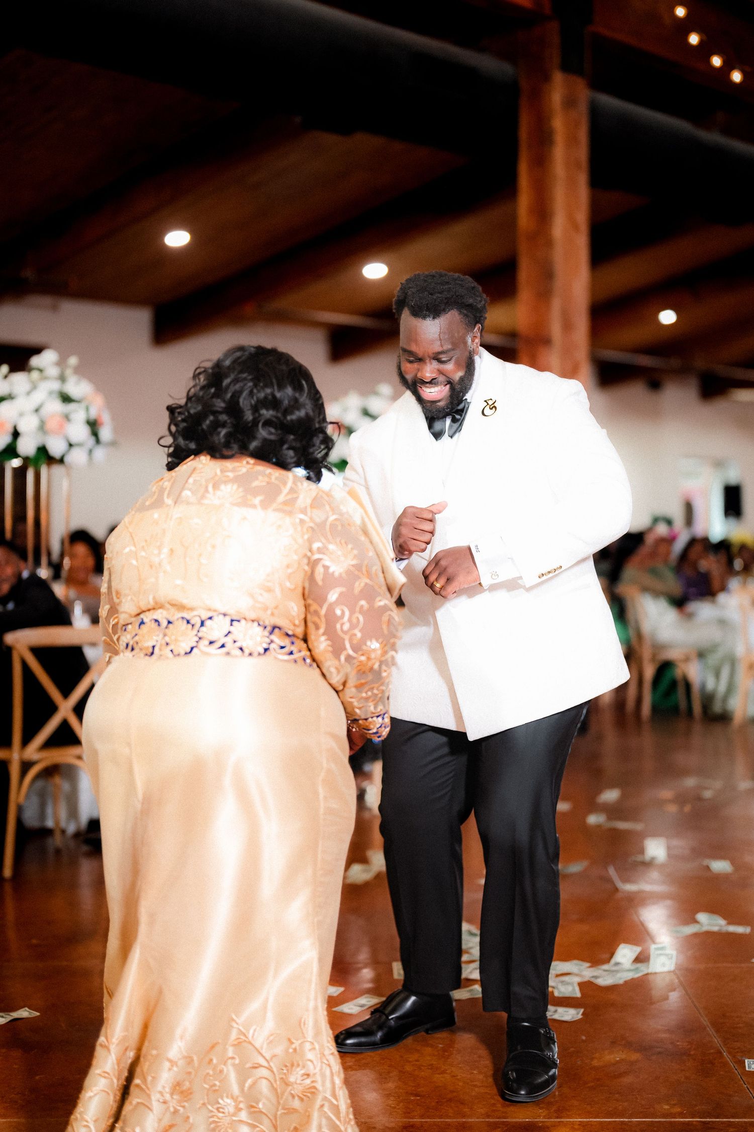 Wedding guests dancing on polished wooden floor during reception celebration.
