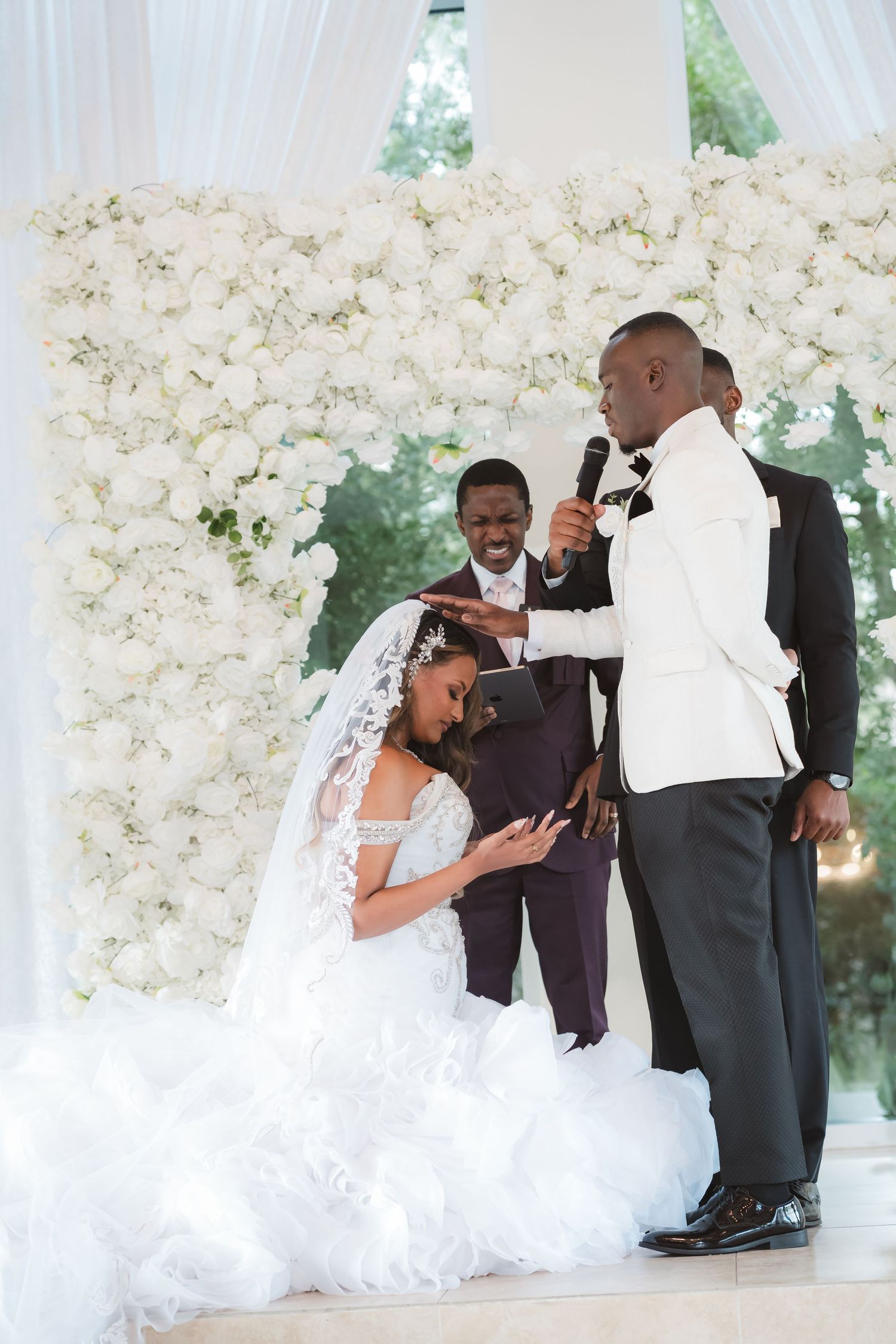 Wedding celebration photos with white floral wall backdrop showing playful dance moves.