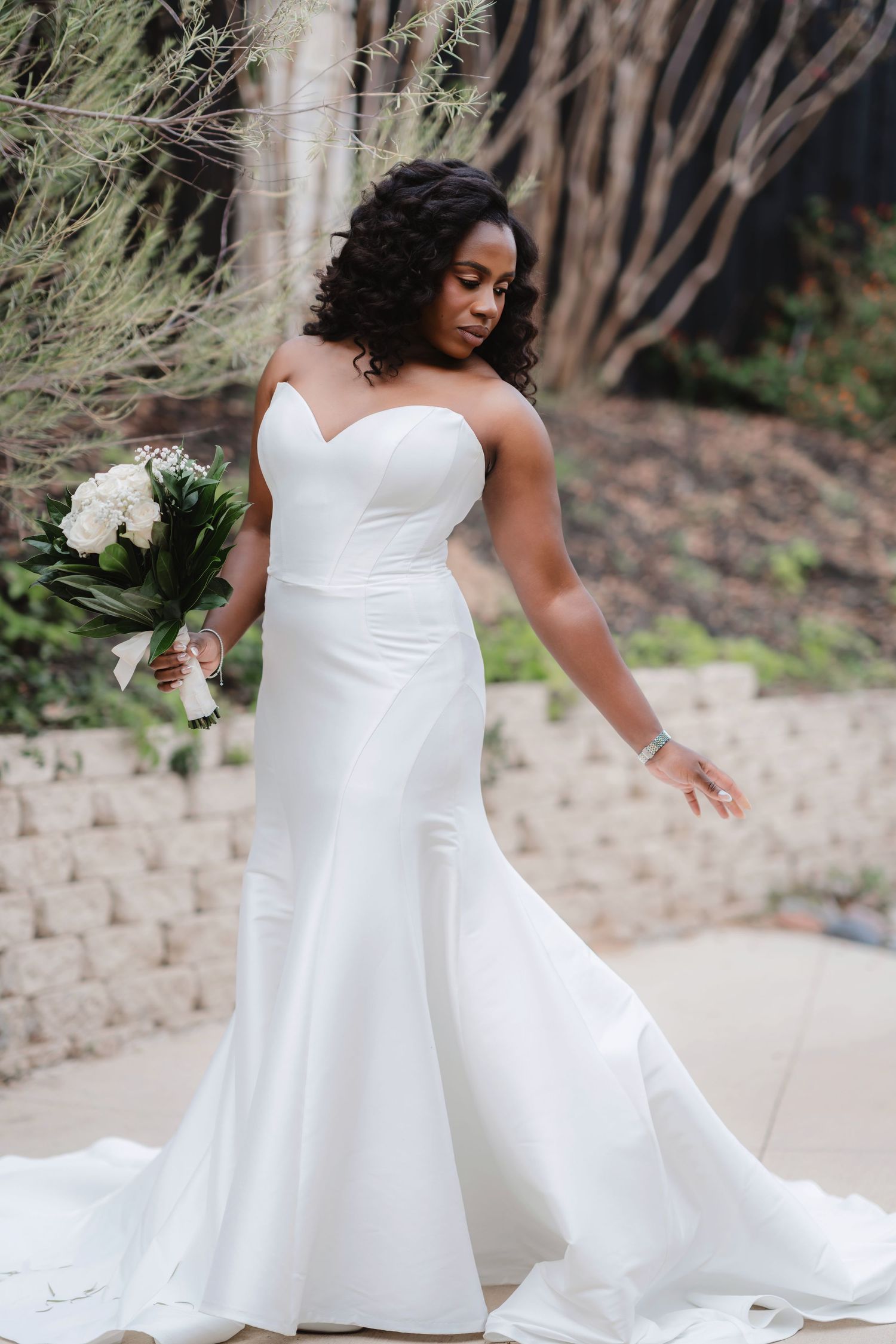Bride in elegant white wedding dress twirls gracefully on stone patio during outdoor photo session.