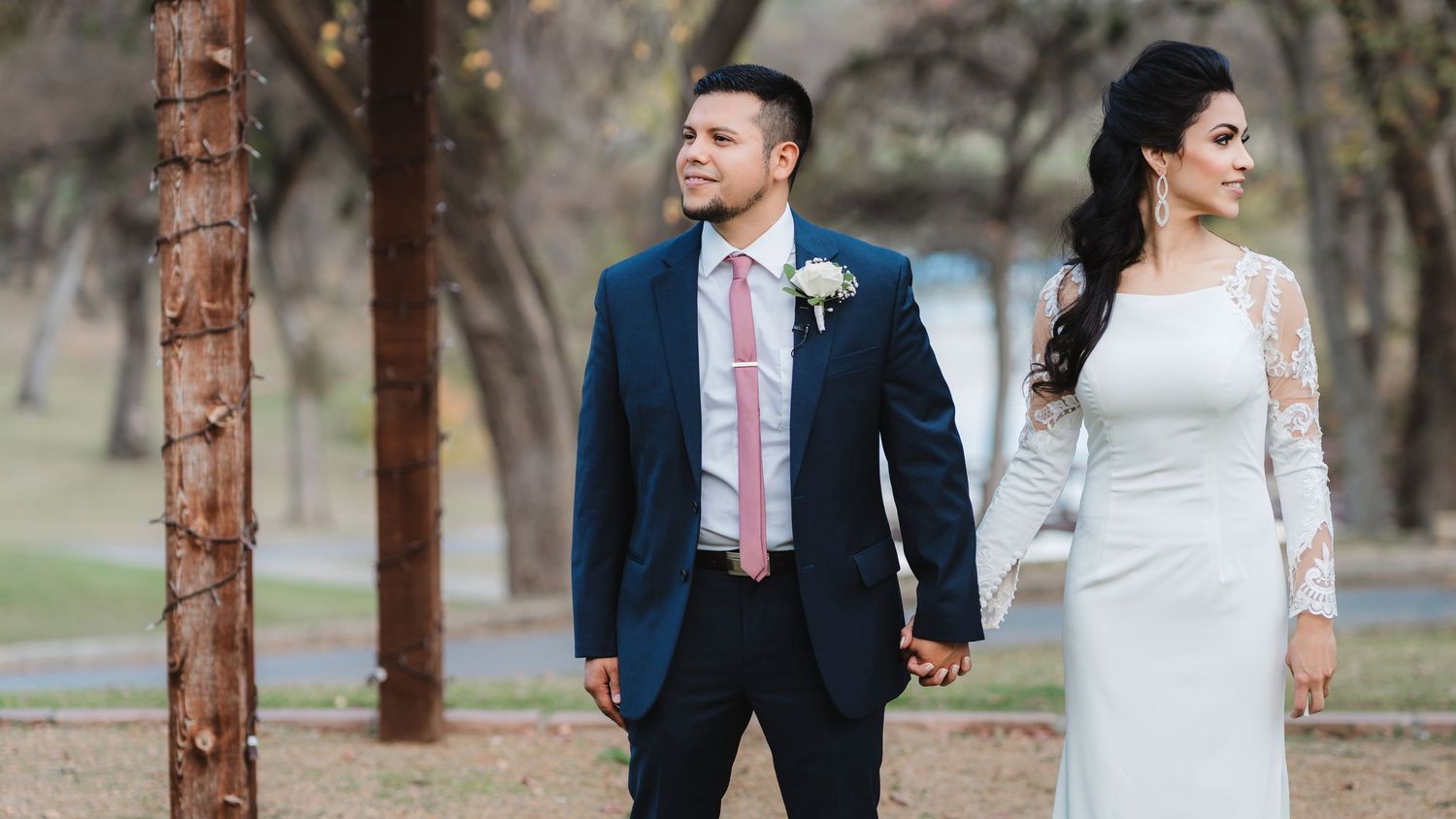 A bride and groom share romantic moments in a park setting with trees during their wedding photo session.
