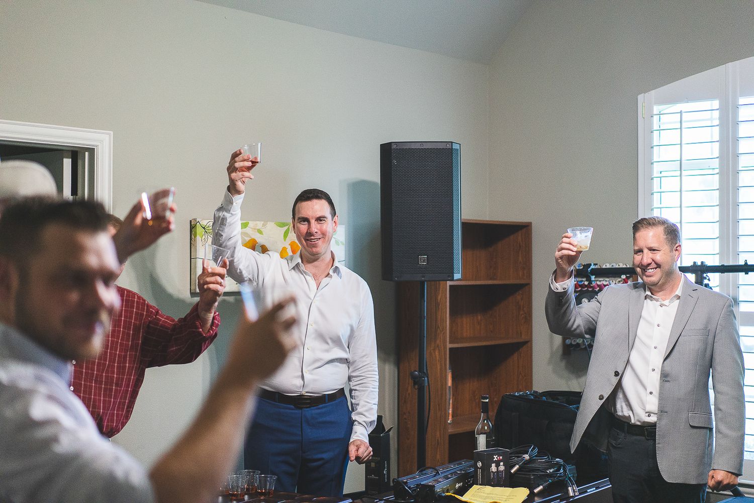 Group celebrating with raised glasses in an indoor setting.