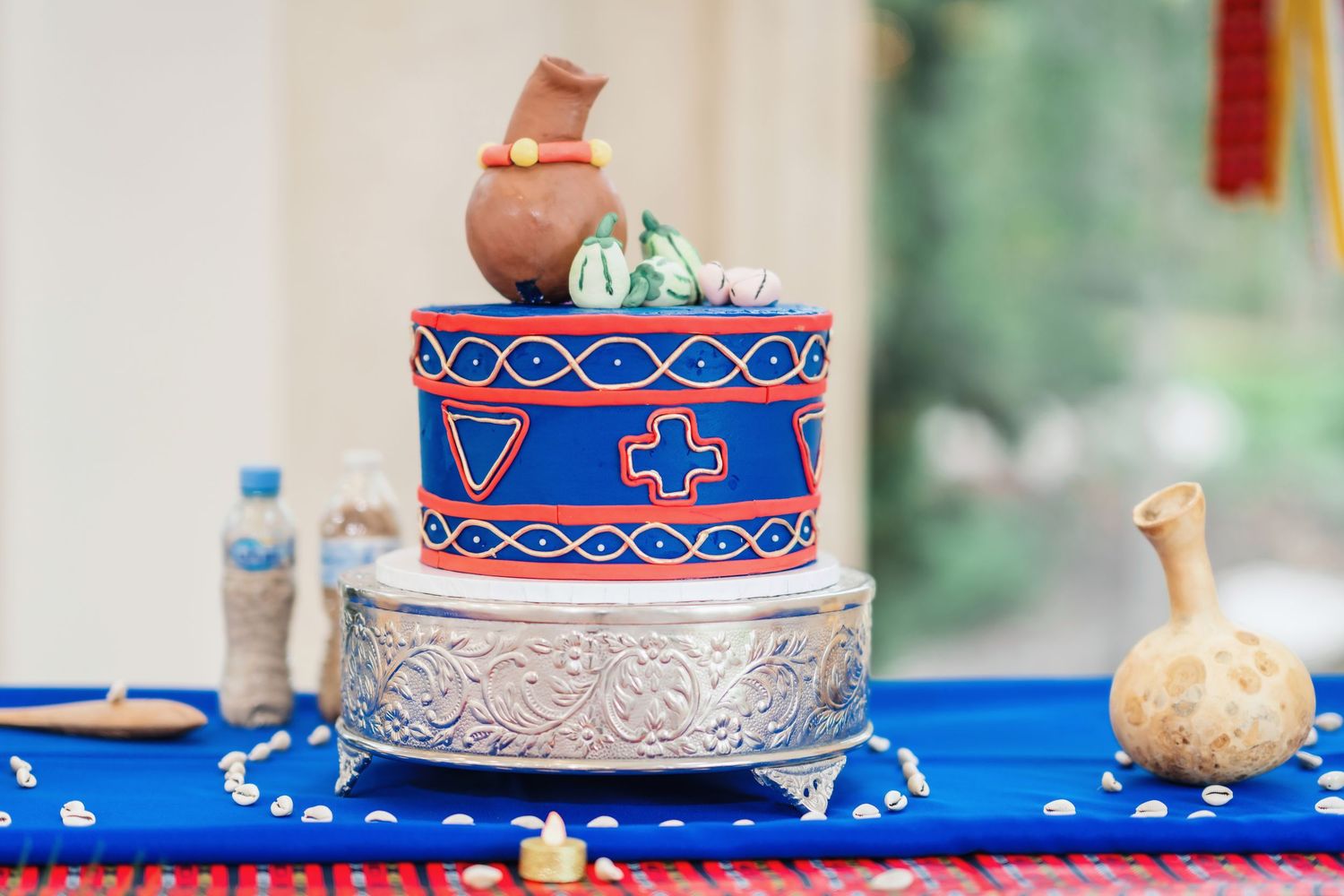 White wedding cake decorated with navy blue and gold details on a blue tablecloth.