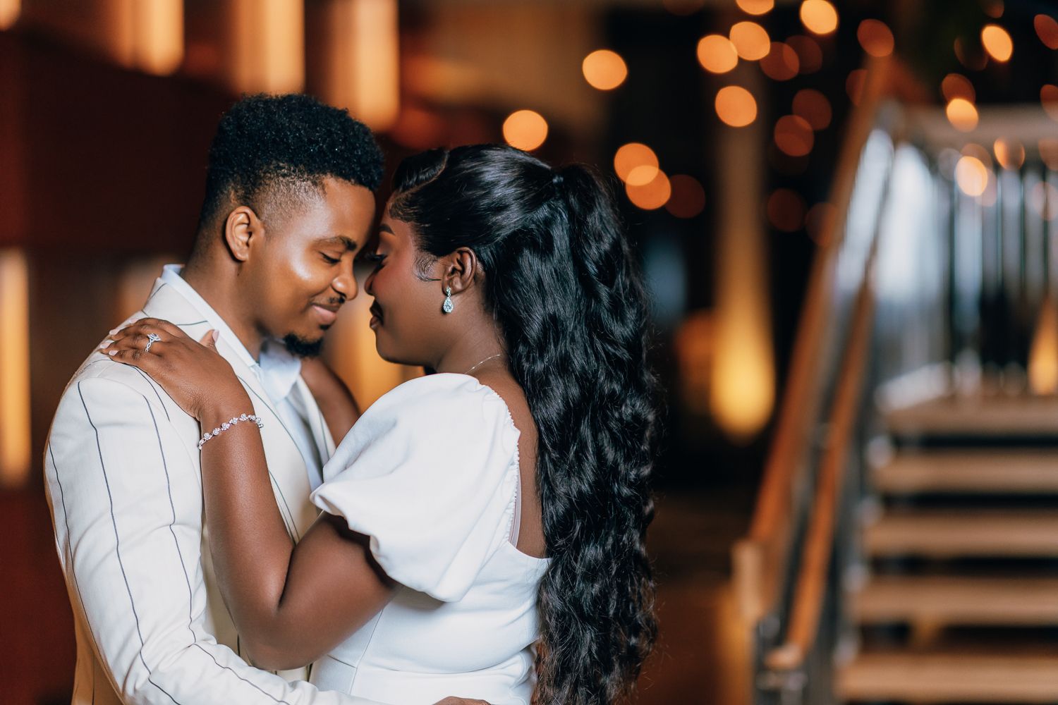 Romantic couple shares tender moments with warm bokeh lighting in the background.