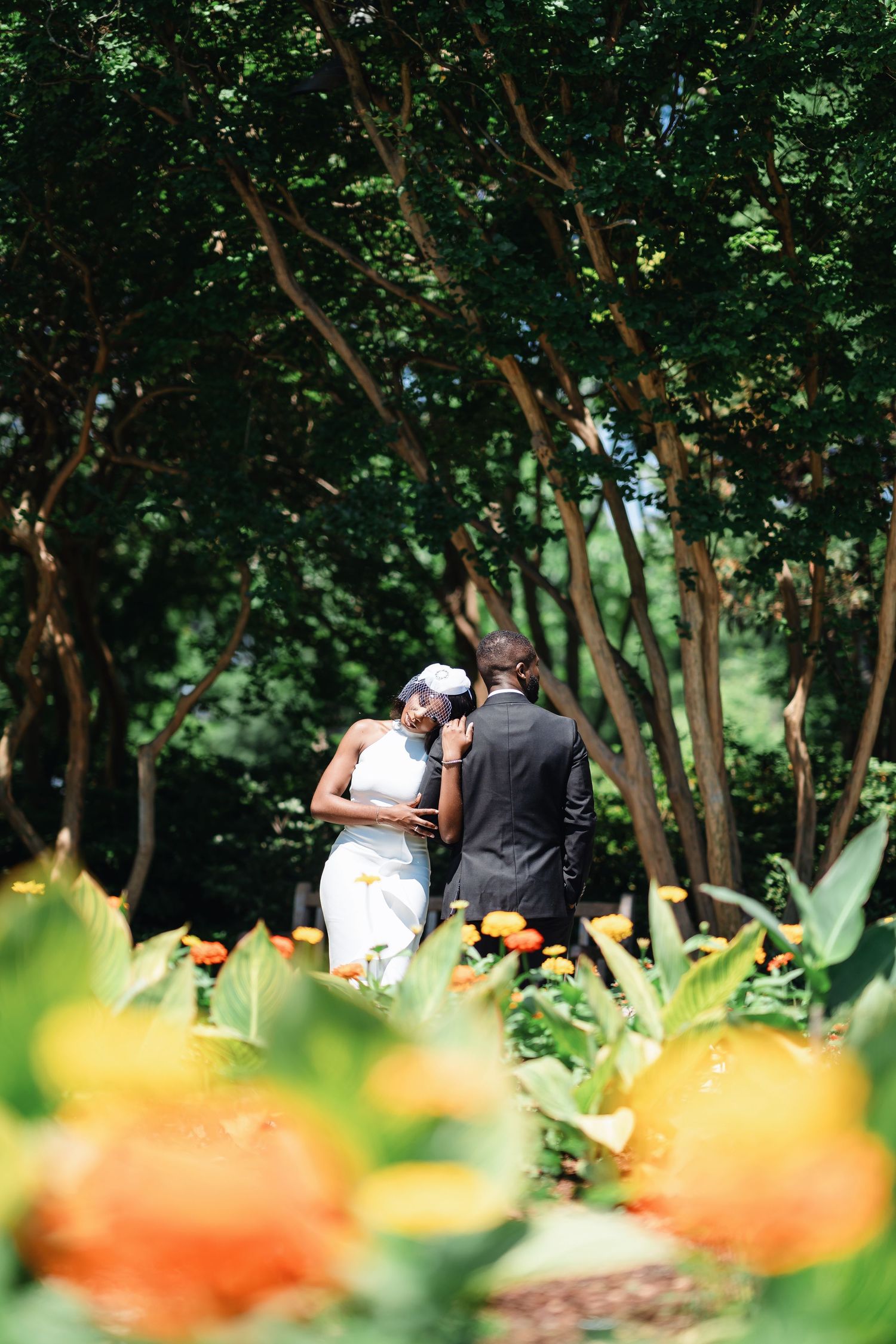 A couple shares an intimate moment in a garden setting with orange flowers in the foreground.