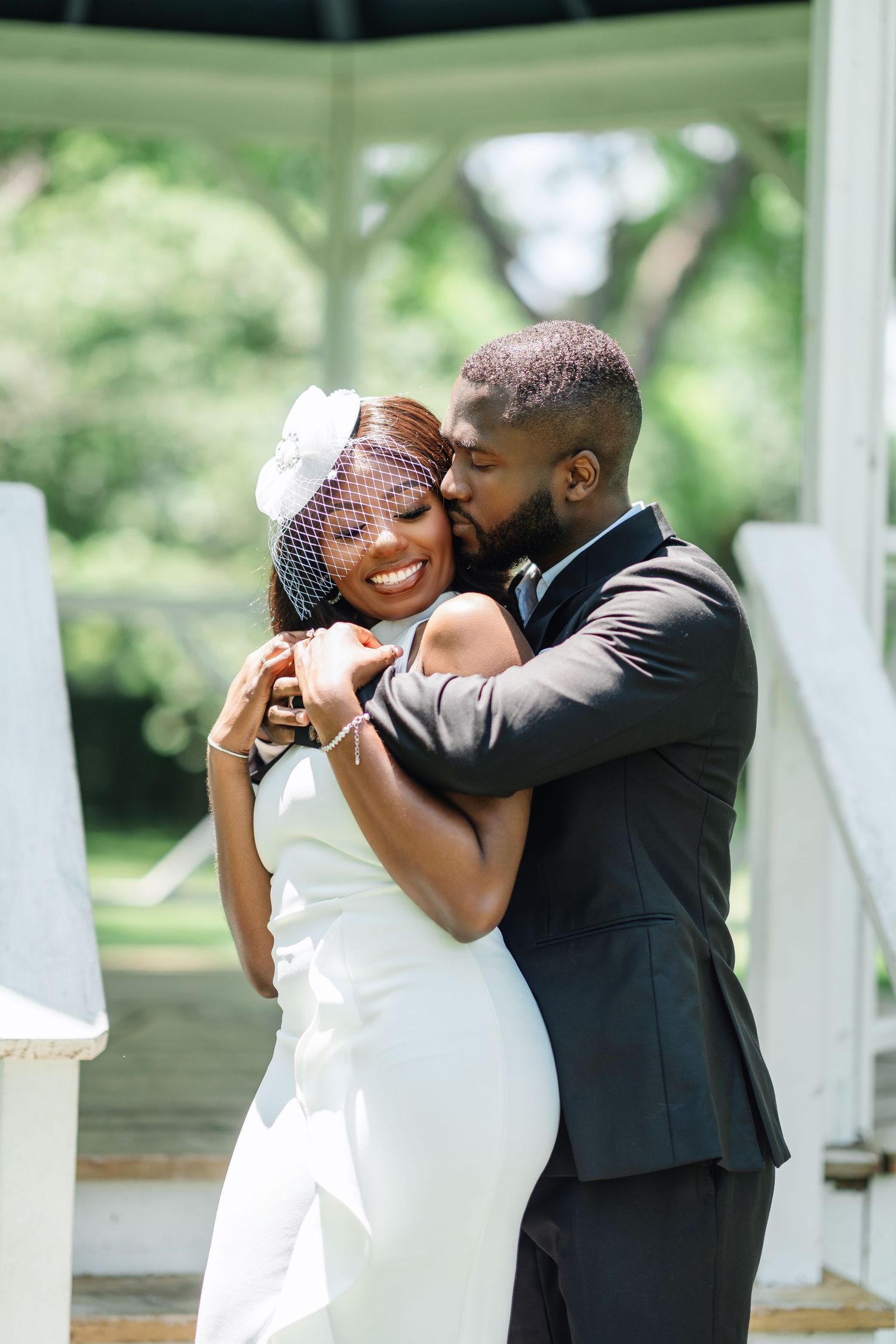 A tender moment between newlyweds as they embrace in a sunlit garden setting.