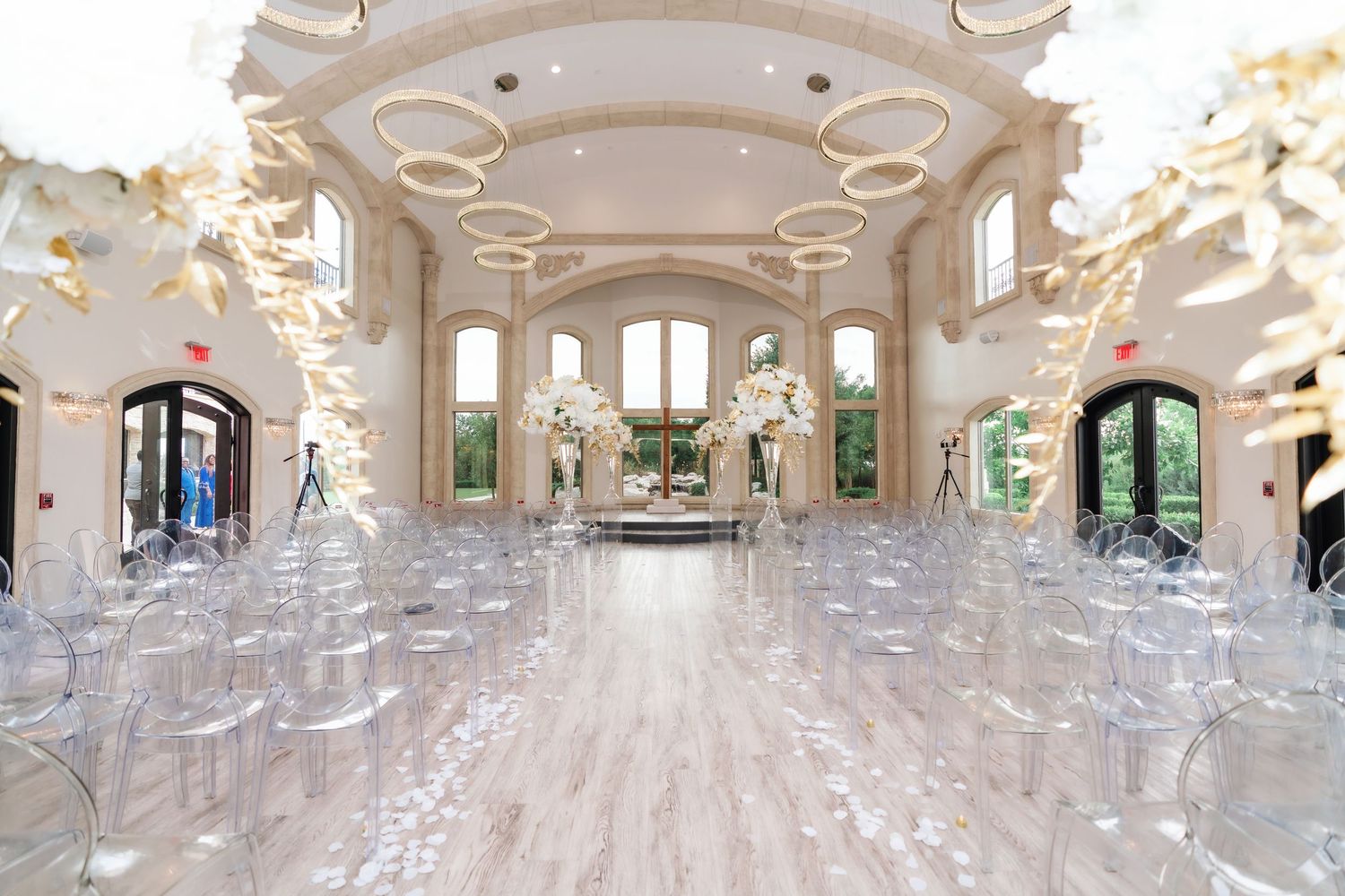 Luxurious ballroom with white ceiling drapes, crystal chandeliers, and elegant table settings for a formal event.