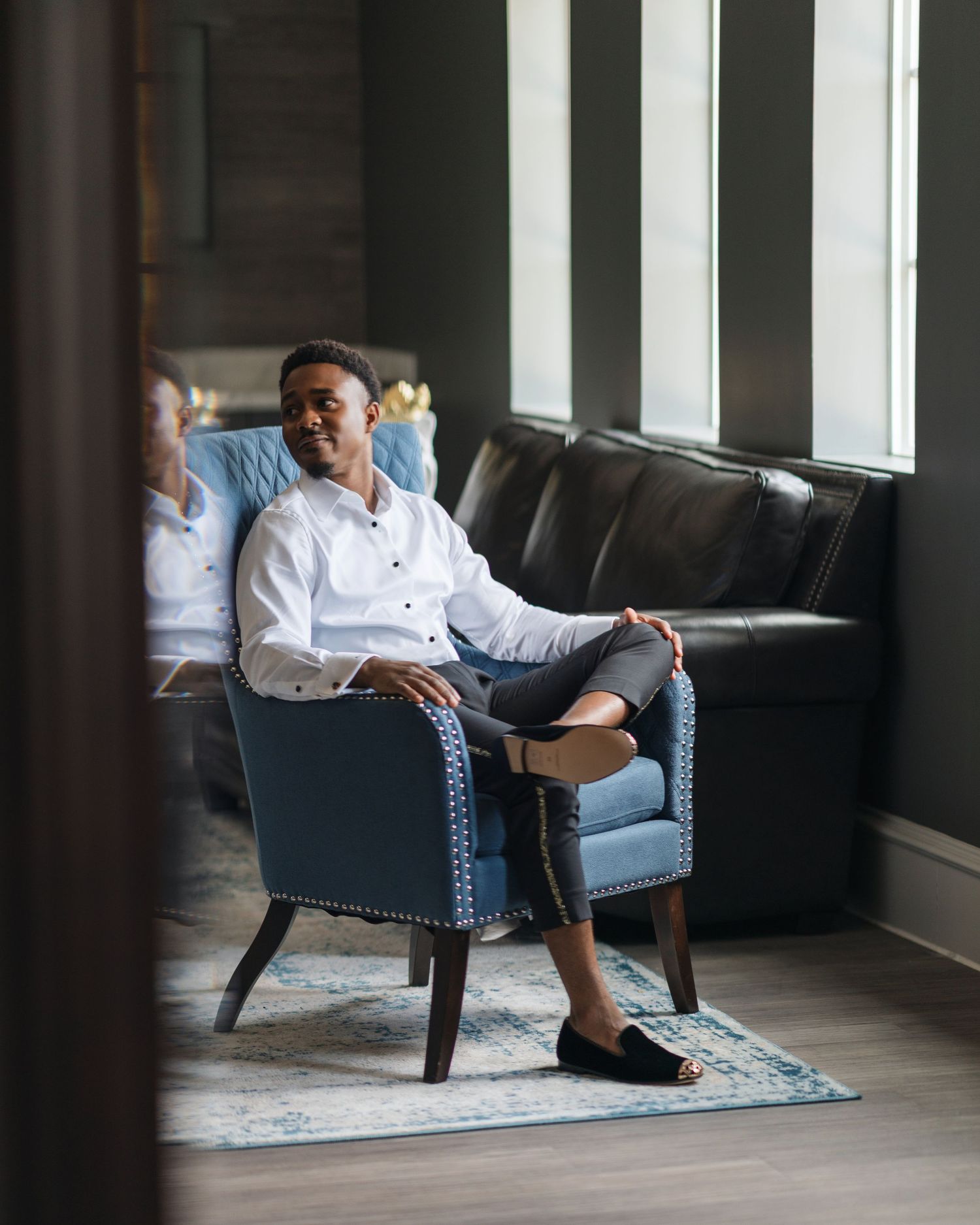 A series of moody indoor portraits showing someone seated in a blue armchair against dark walls.