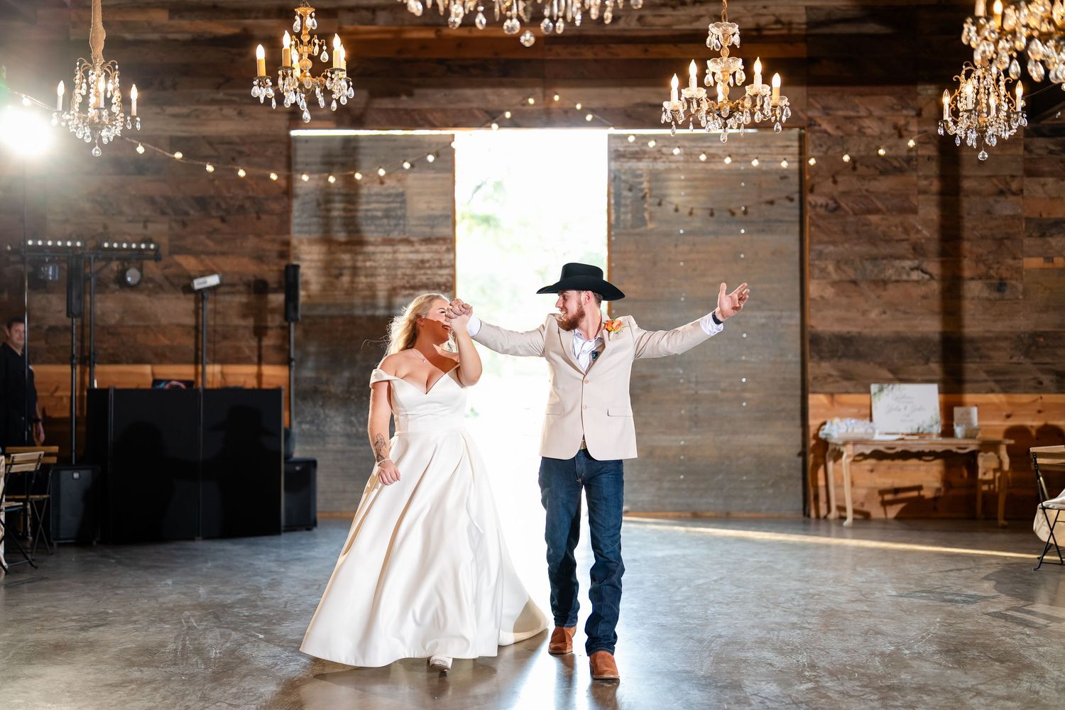 Elegant rustic wedding venue with chandeliers and string lights creating a romantic atmosphere.