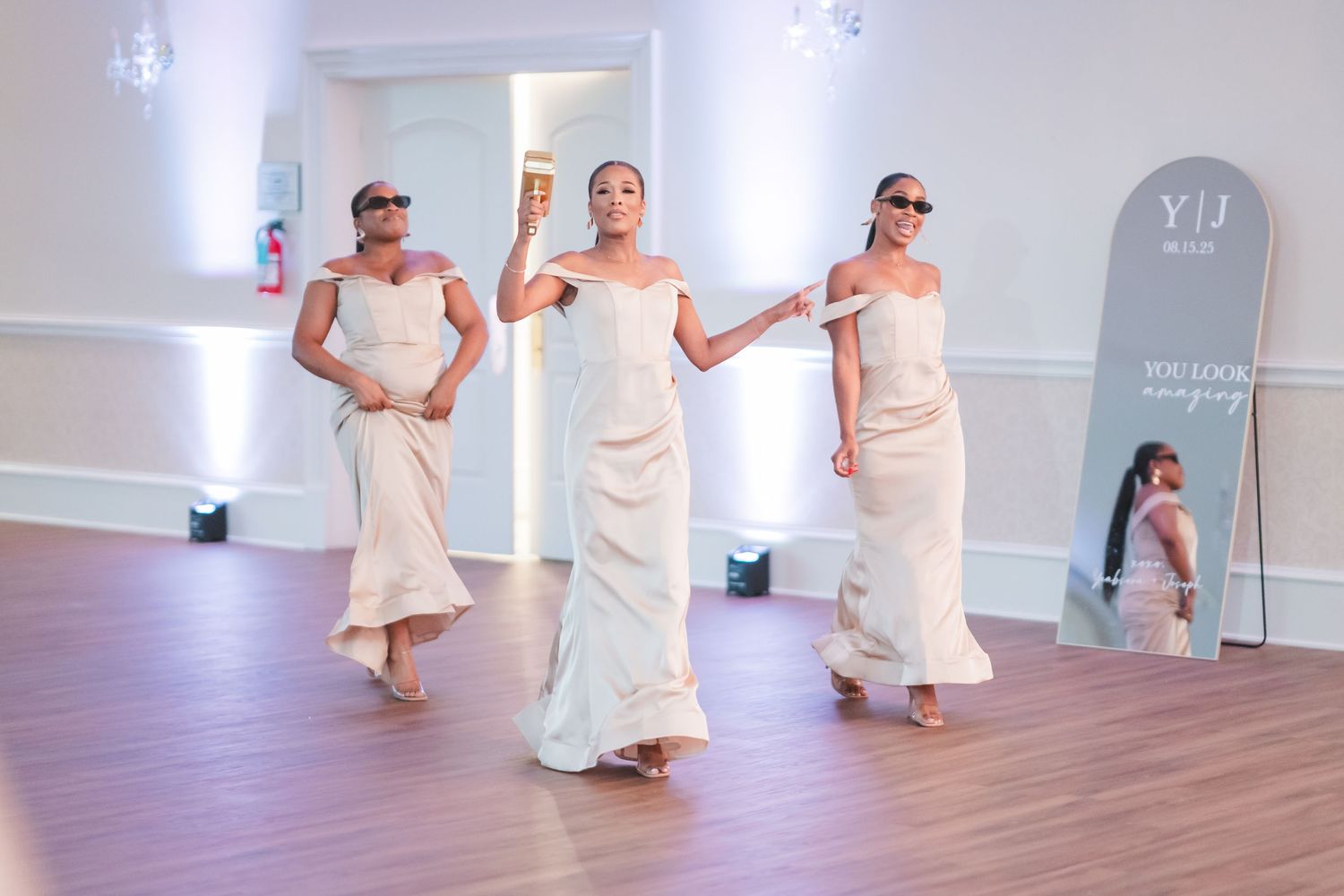 Wedding party members in white dresses dancing in synchronization on wooden floor.