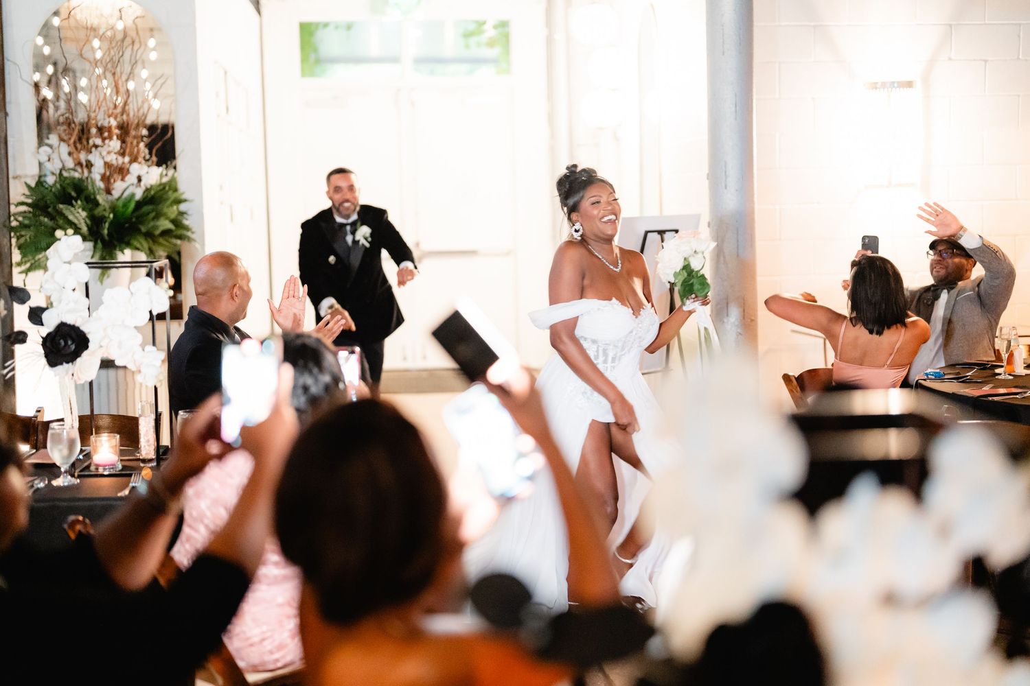 Wedding celebration crowd cheers with raised hands during reception festivities.