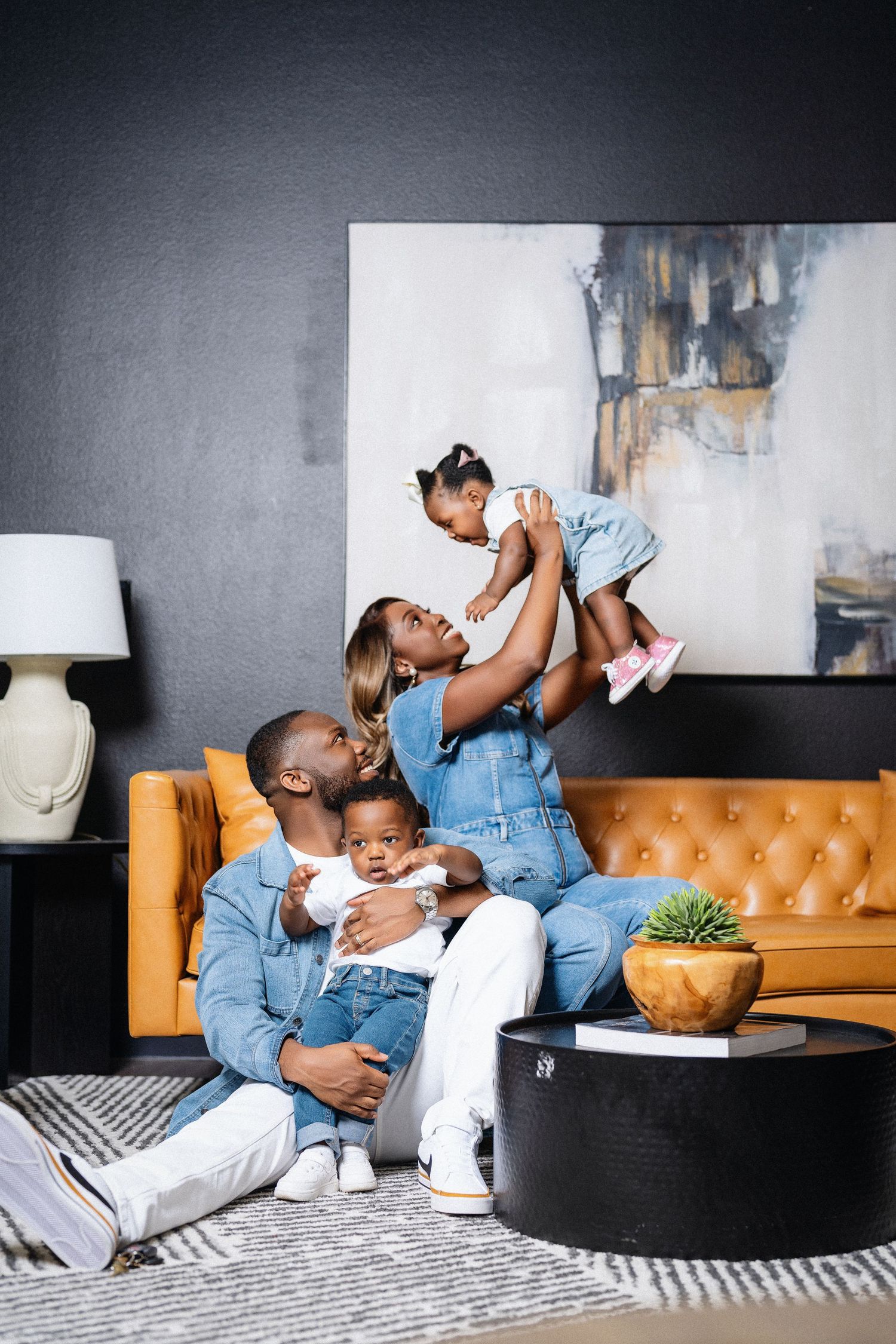 Playful family moments captured on a tan leather couch with modern home decor elements.
