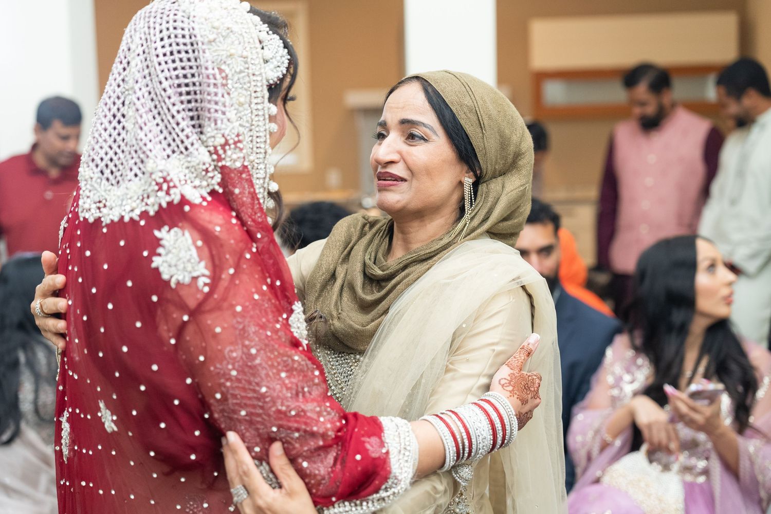 Wedding celebration scene showing guests in traditional attire at an indoor venue with festive decorations.