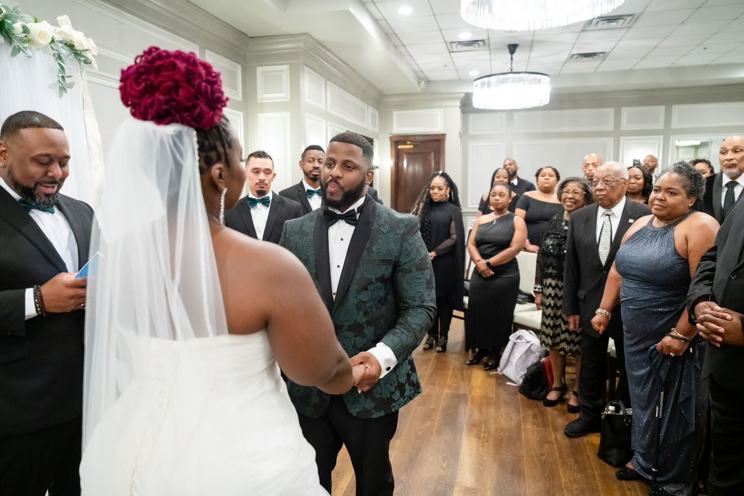Wedding ceremony guests gathered in an elegant indoor venue with bright lighting.