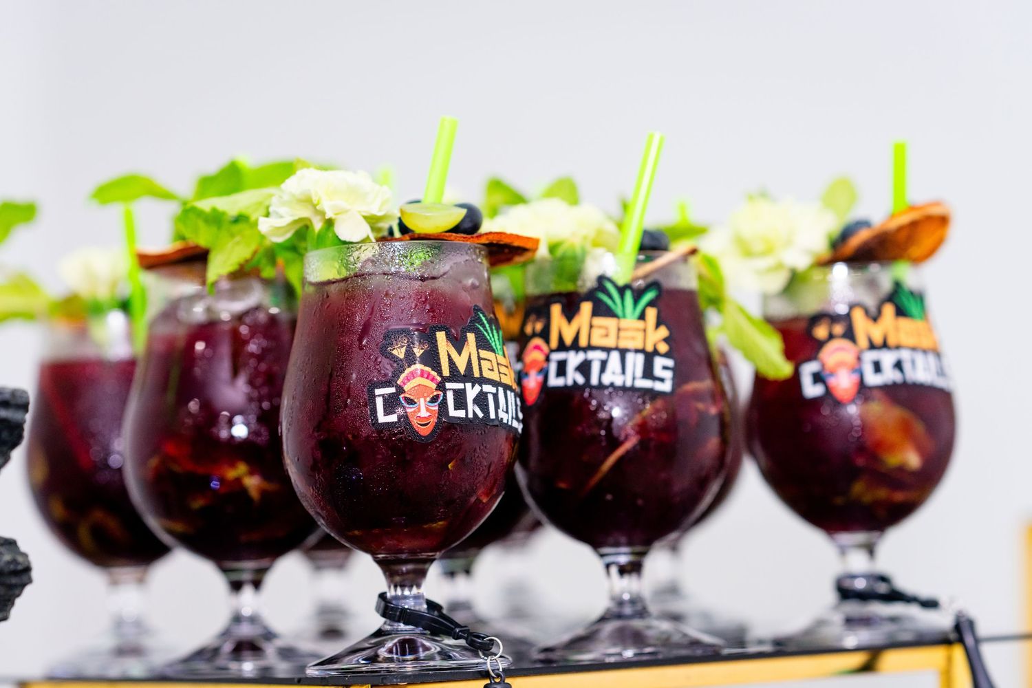 Red sangria cocktails garnished with fresh mint and fruit slices are served in stemmed glasses at a bar.