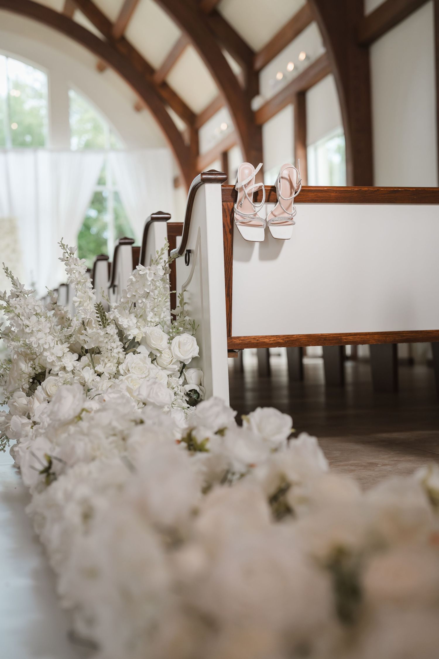 Elegant white floral centerpieces line a rustic wooden beam ceiling venue.