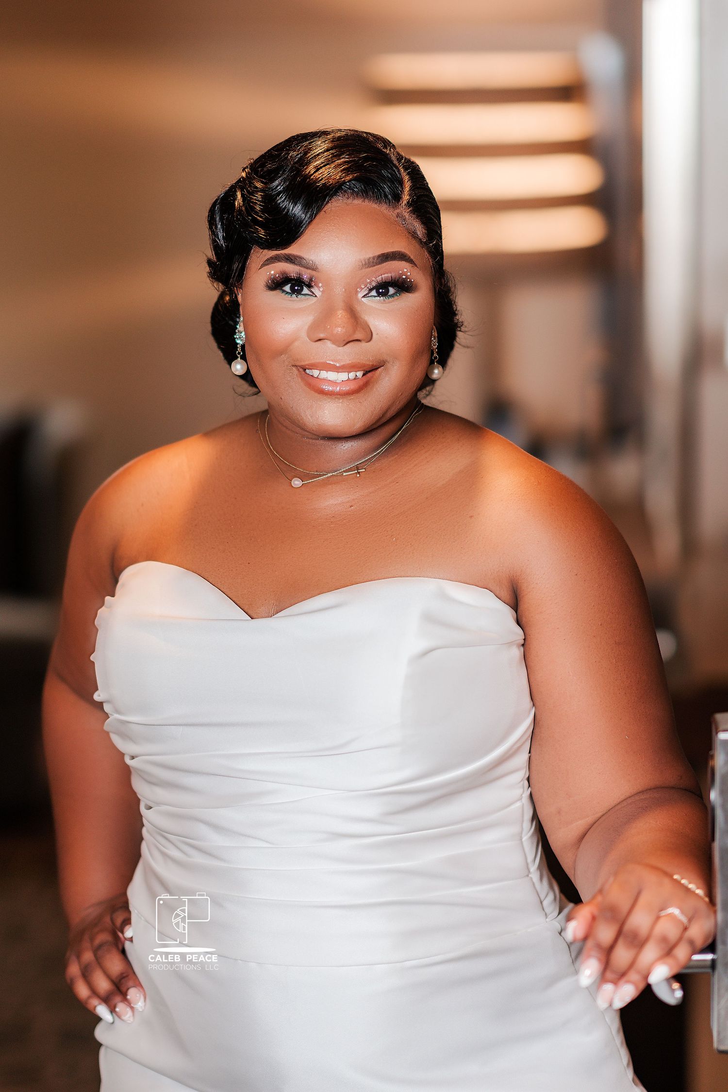Beautiful bride in a strapless white wedding dress smiling warmly at the camera.