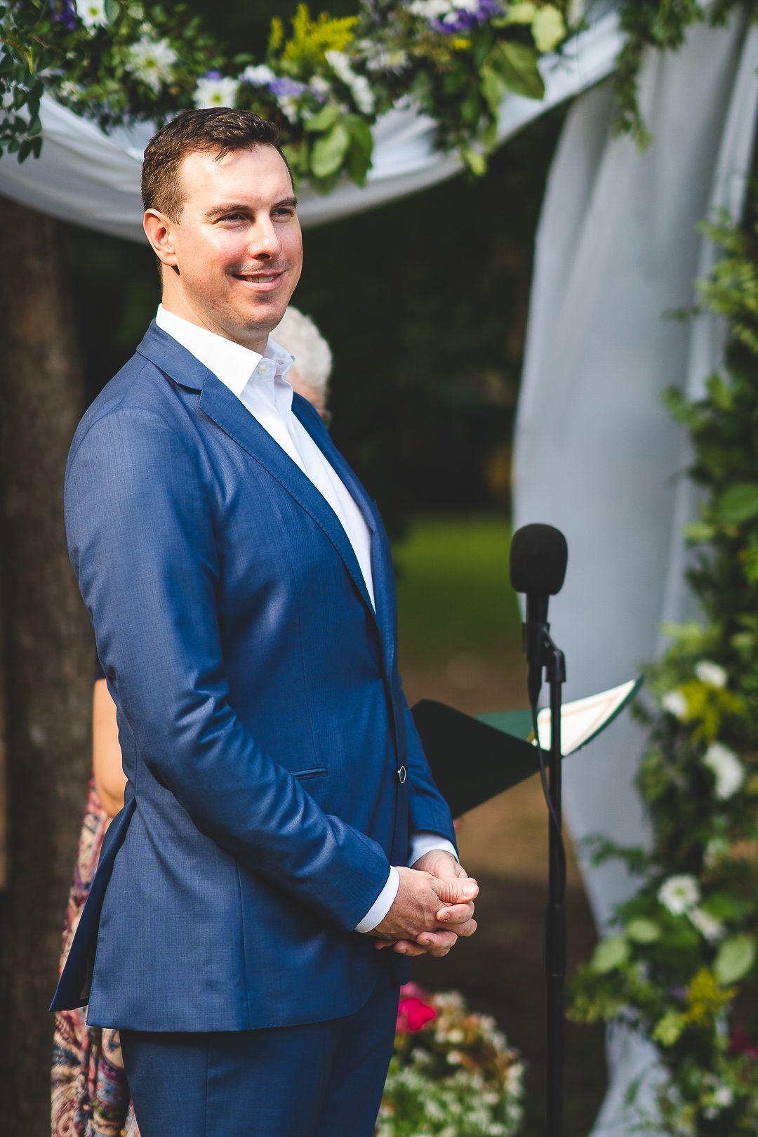 Wedding ceremony setup with decorative white fabric draped between trees and floral arrangements.