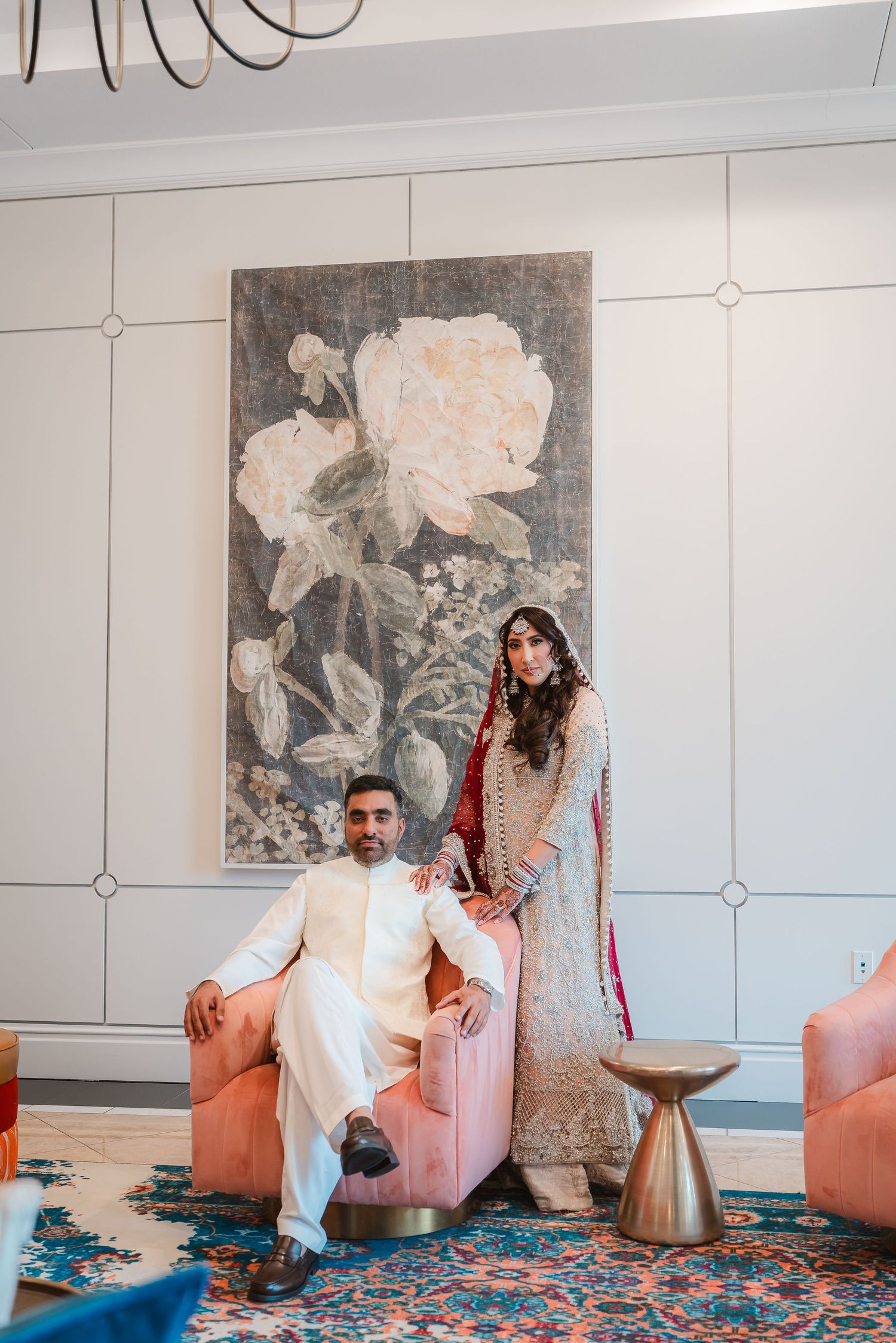 Wedding couple poses in front of modern wall art in an elegant indoor setting.
