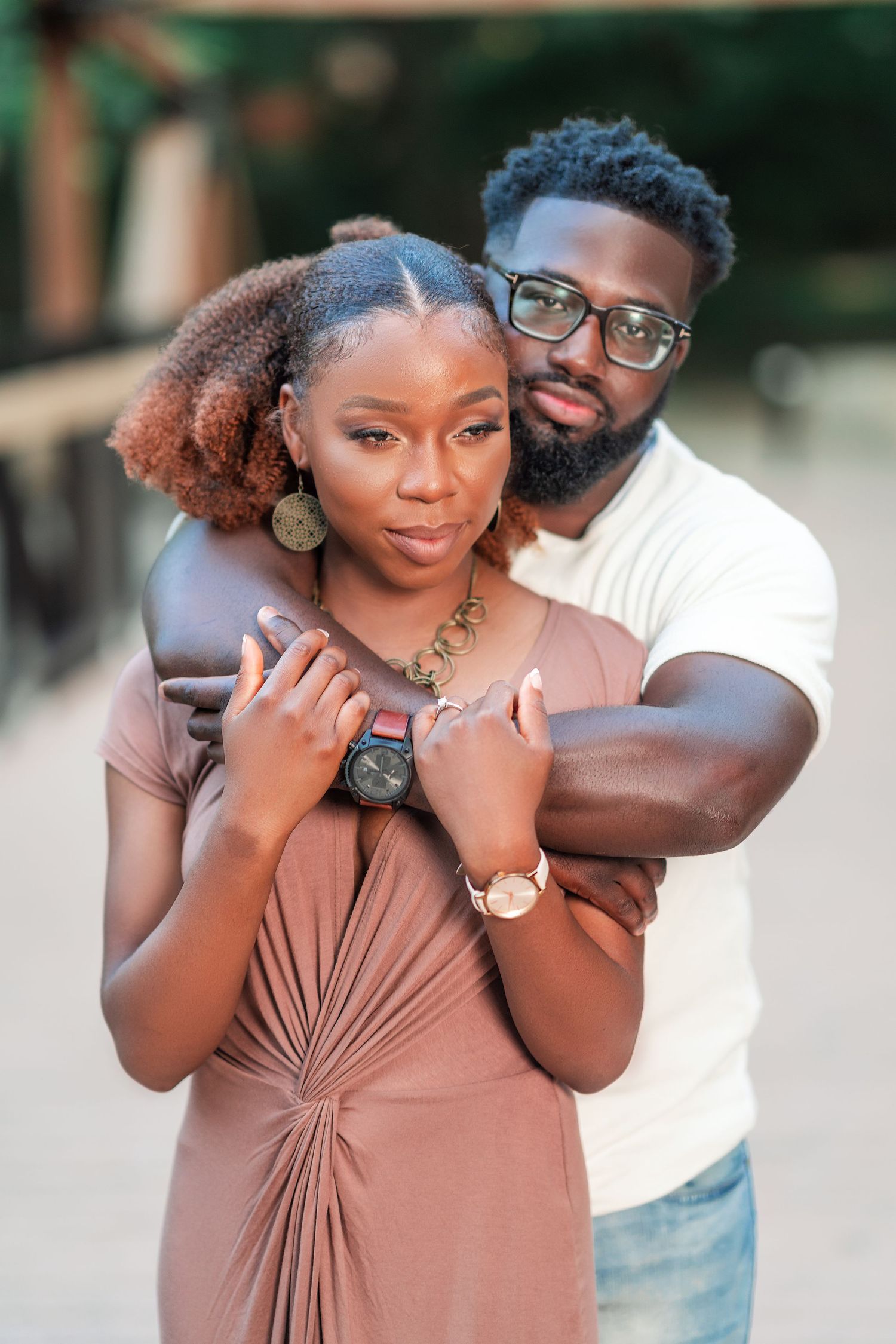 A romantic couple embraces in matching earth-toned outfits during an outdoor photoshoot.