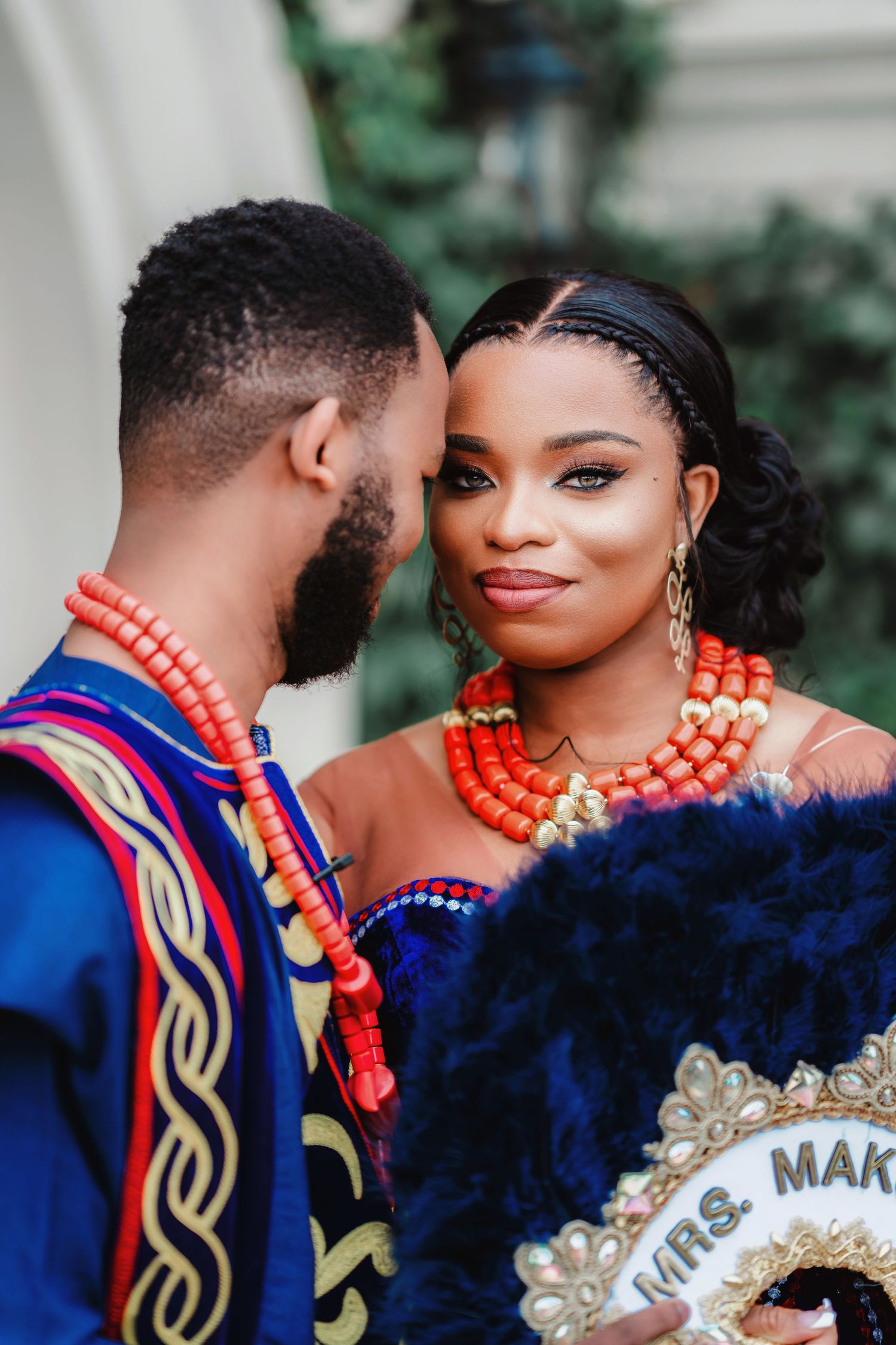 A couple in traditional wedding attire with blue and orange accents pose for romantic portraits.