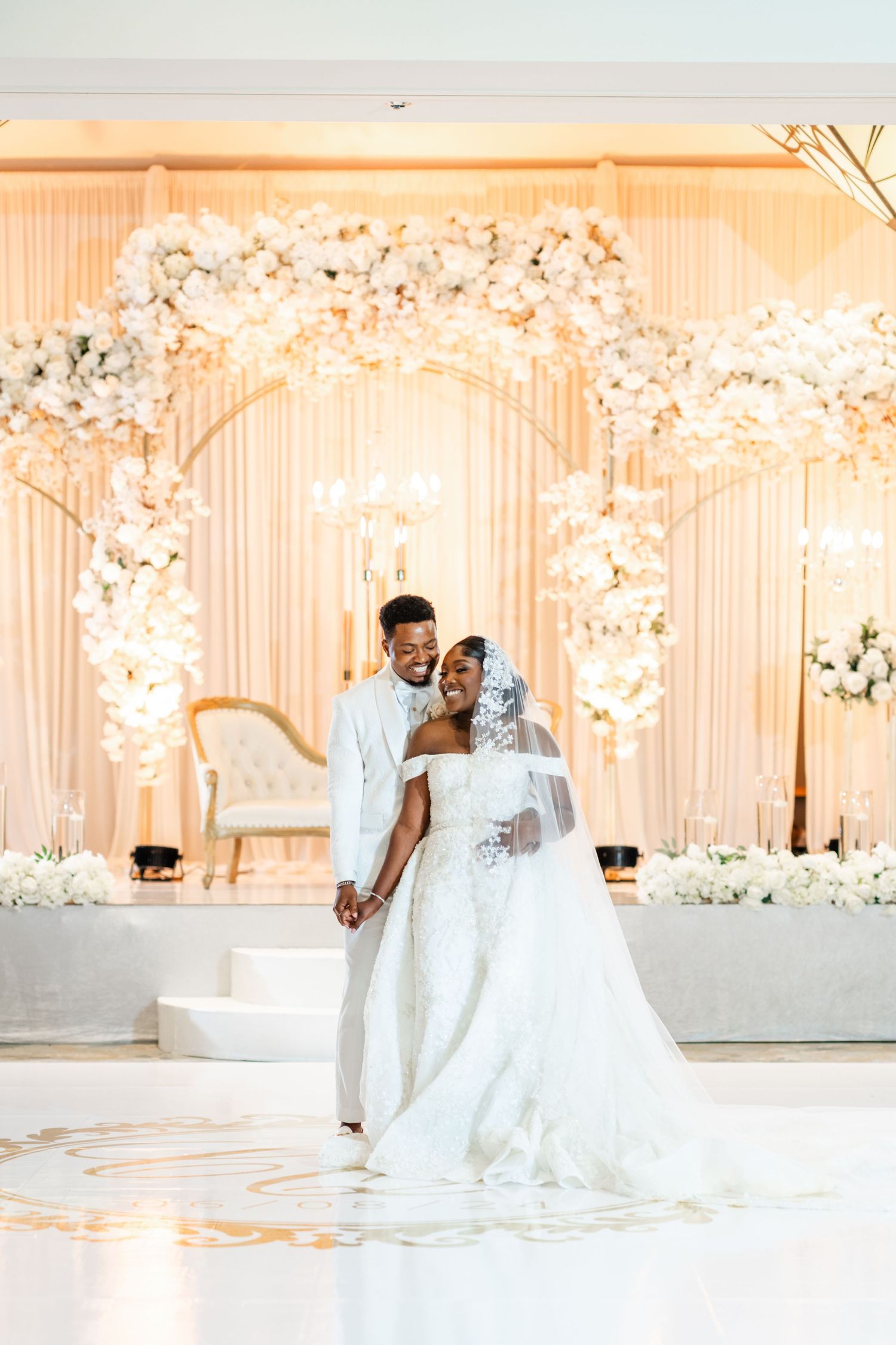 Elegant wedding venue with white floral decor and soft peach lighting creates a romantic atmosphere.