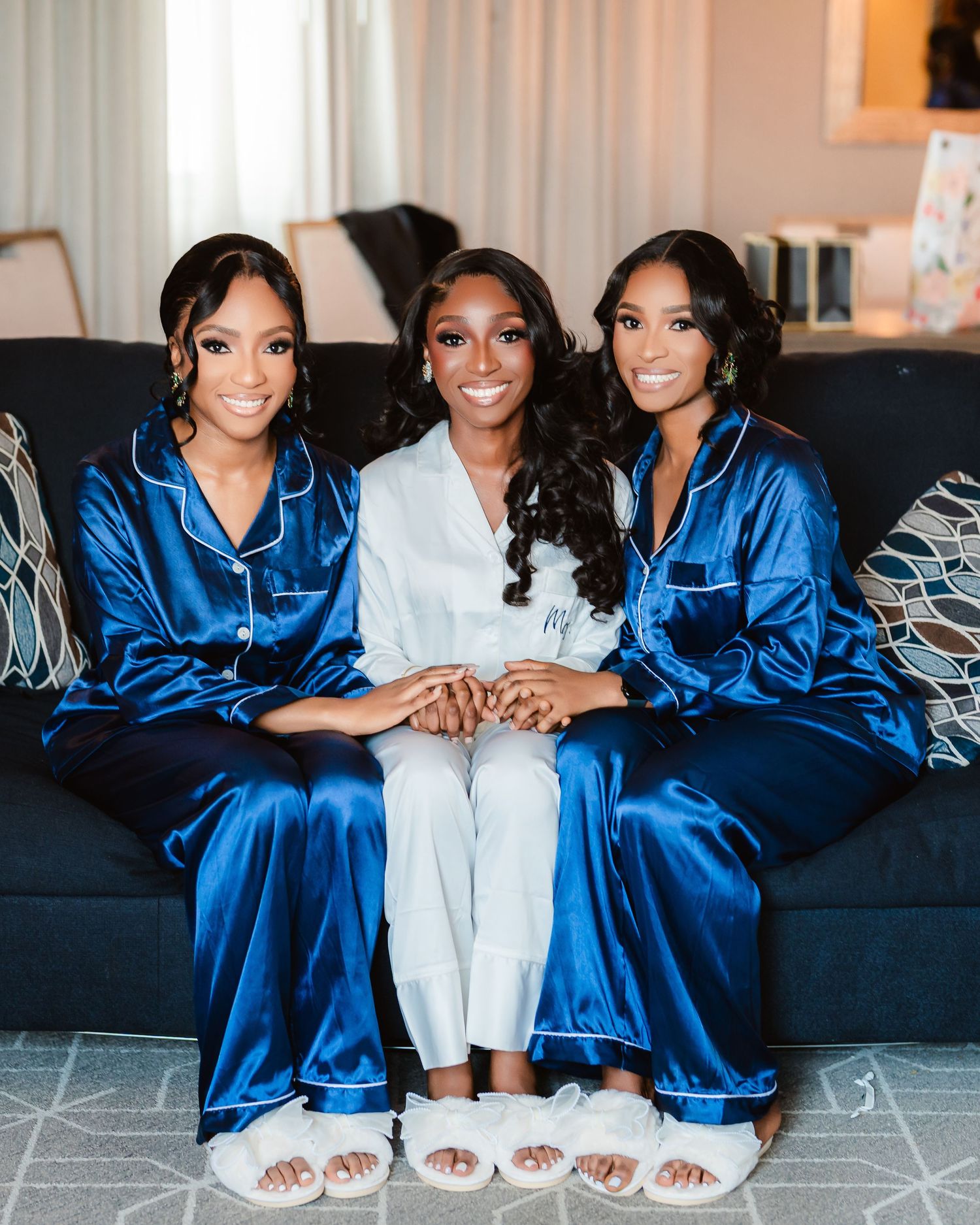 Bridal party relaxing on a dark couch wearing coordinated royal blue silk robes.