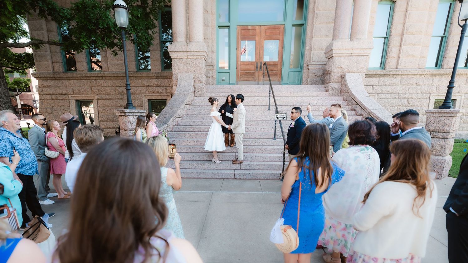 Wedding guests gather outside a venue during a celebration.