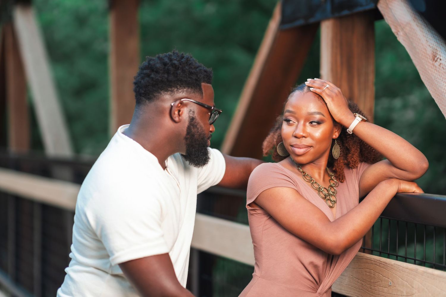 A couple shares a playful moment on a wooden bridge during their photoshoot.