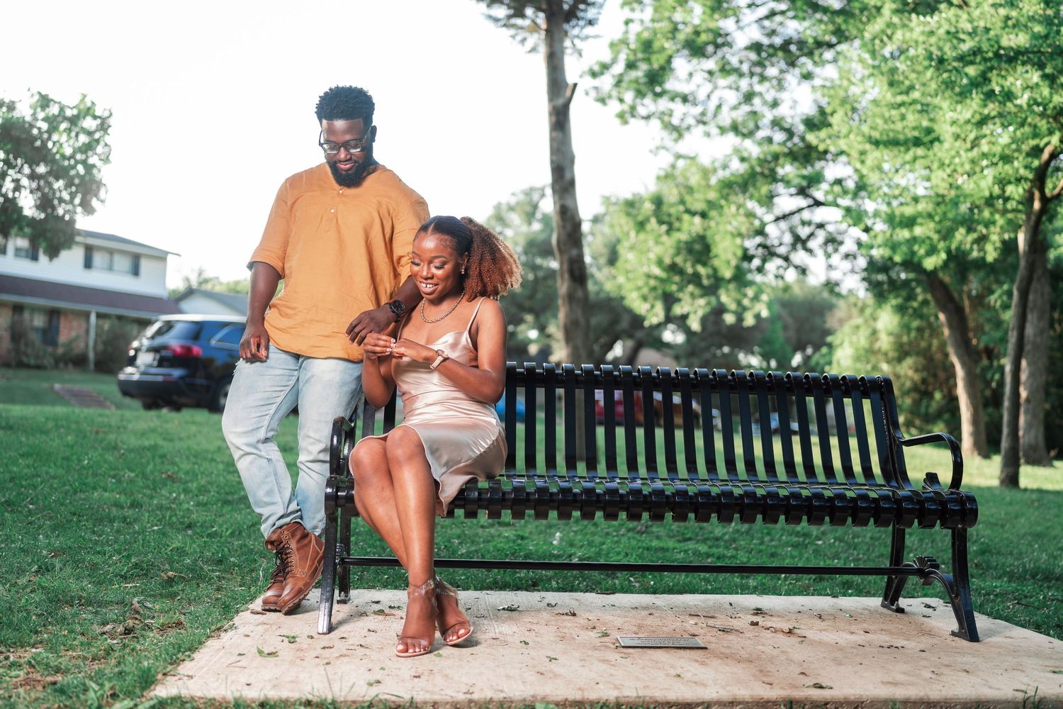A couple sits together on park benches during an outdoor photoshoot.