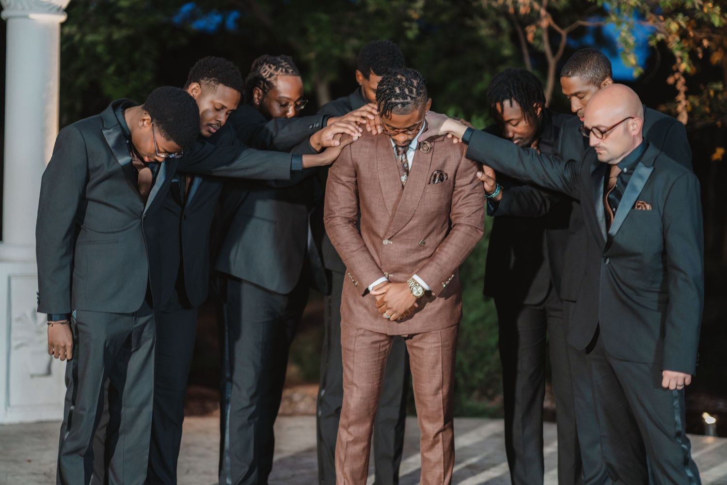 Wedding party members in formal attire gather outdoors for group photos.