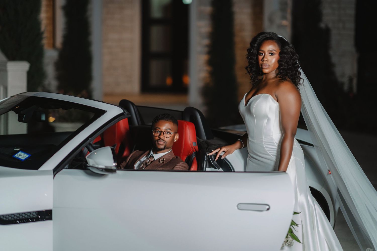 Wedding couple exits in a classic car with the bride in white and groom in brown.